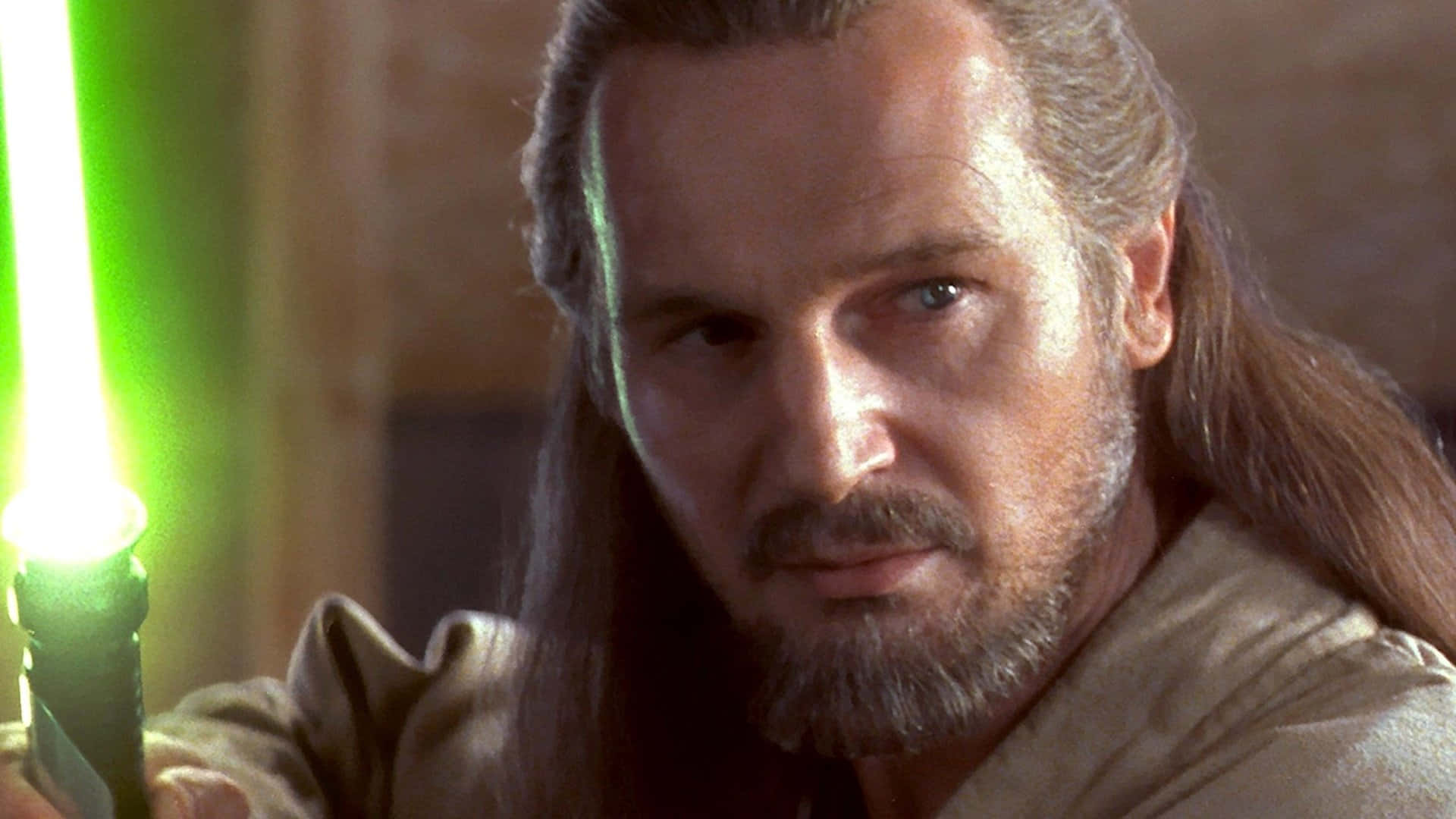 Qui-gon Jinn 桌布 壁紙 — 一位長灰髮的絕地大師在昏暗的房間中手持發光綠色光劍的特寫。
