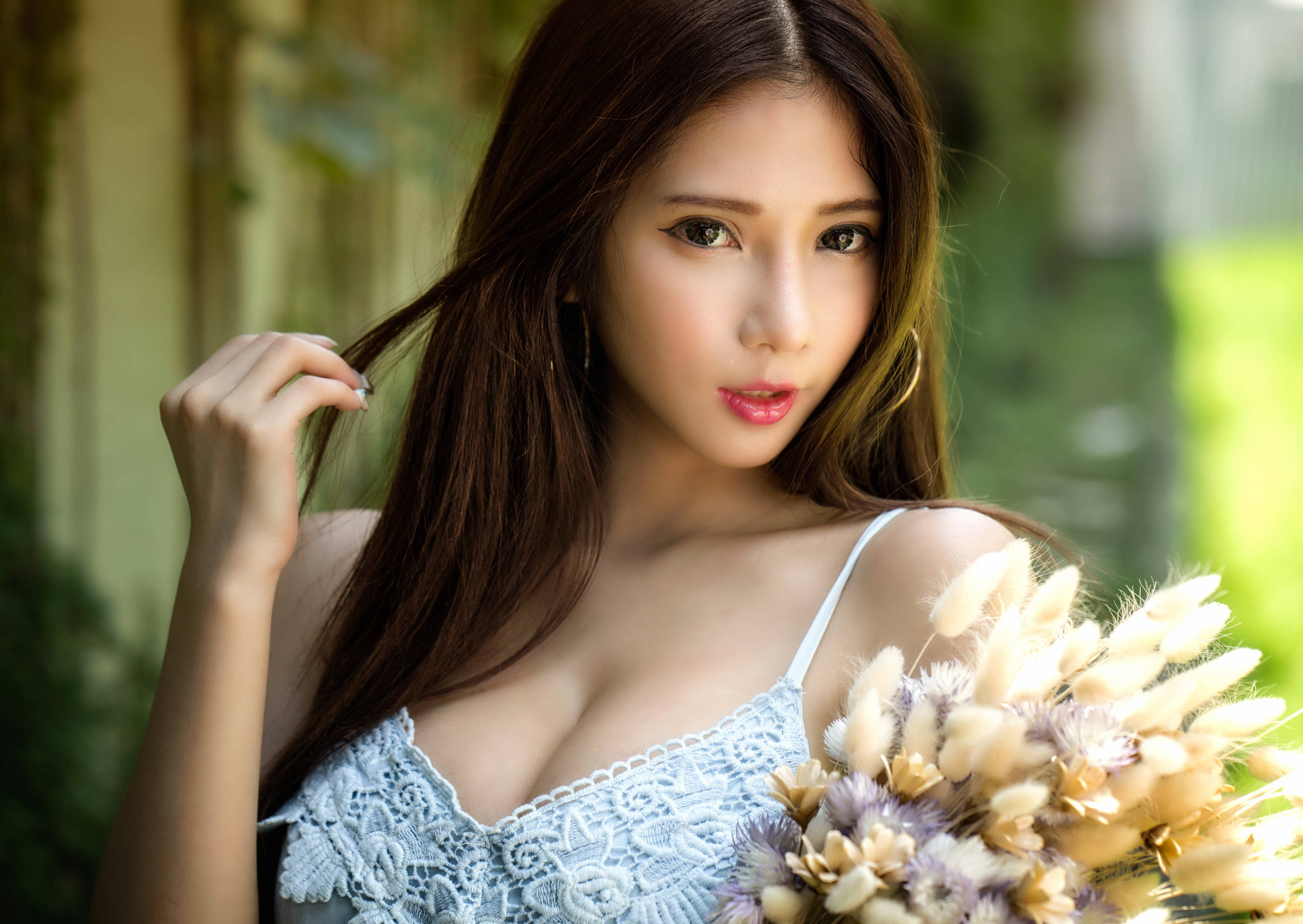 美女 桌布 壁紙 — 一位長著棕色長髮的年輕女性在陽光明媚的花園中手持乾花，溫柔地凝視著鏡頭。