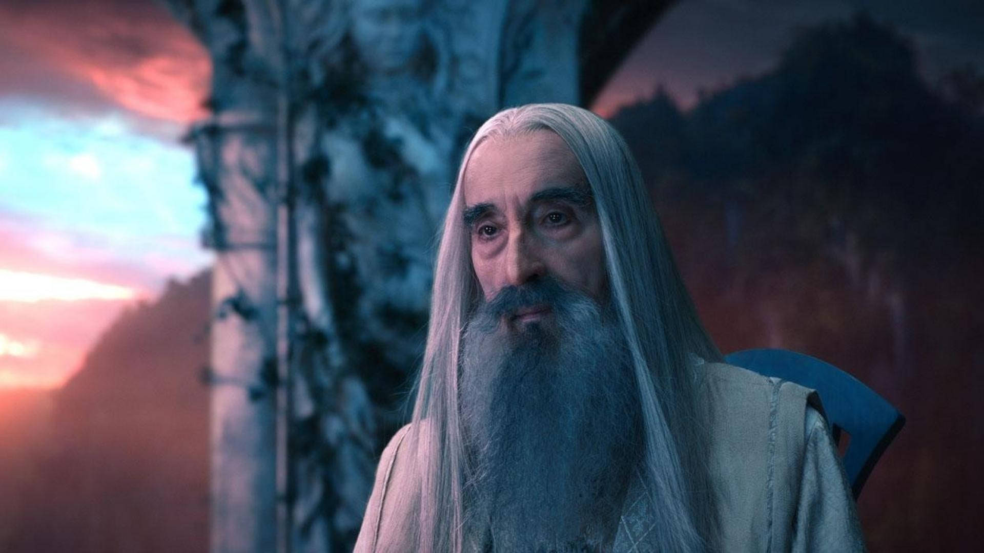 魔戒 桌布 壁紙 — 一位長著白色長髮和鬍鬚的年長巫師，在帶有粉紅色和藍色色調的暮色天空下莊嚴地凝視著。
