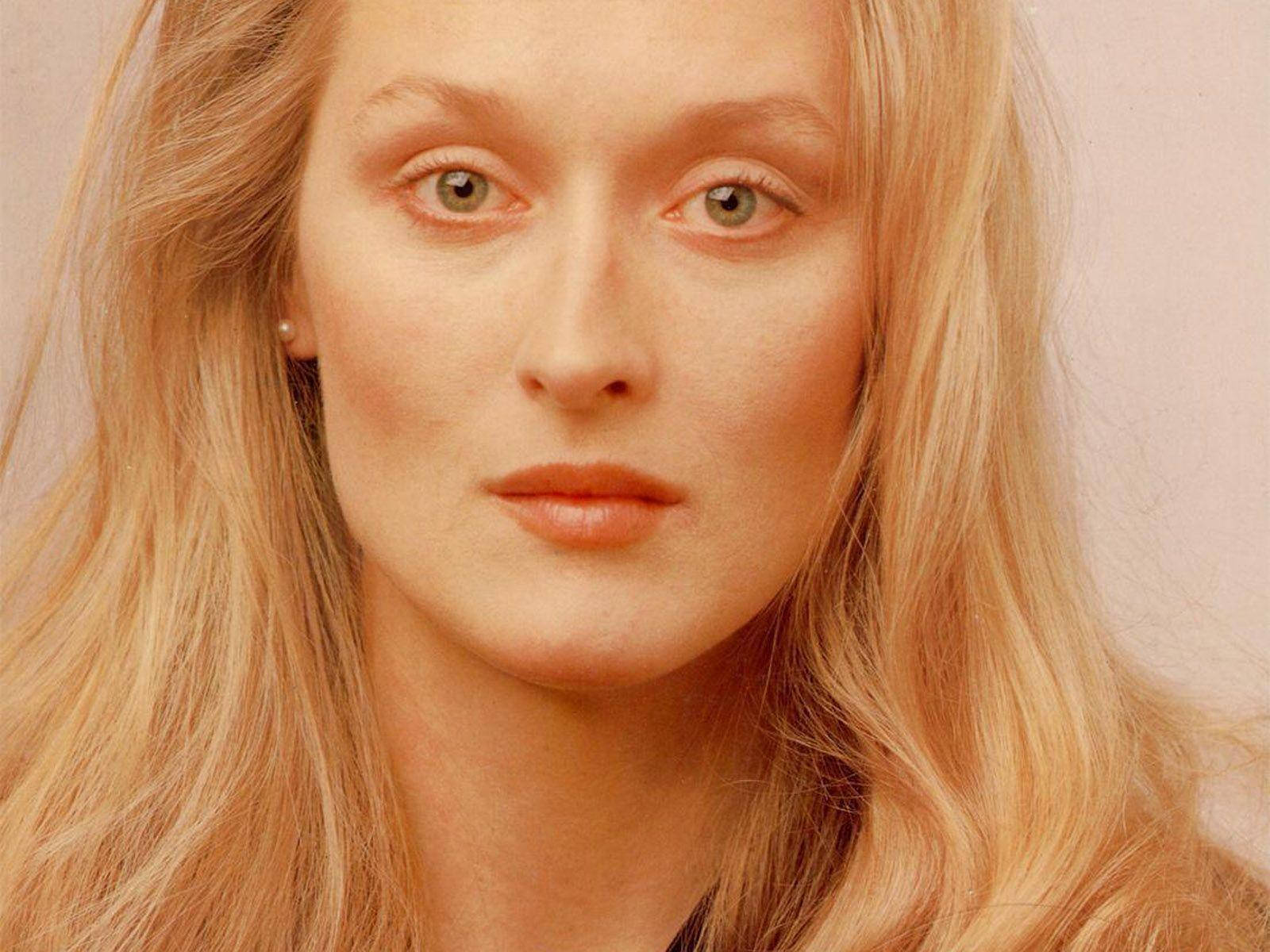 Meryl Streep 桌布 壁紙 — 一位長金髮、柔和綠眼女性冷靜凝視鏡頭的近距離肖像。