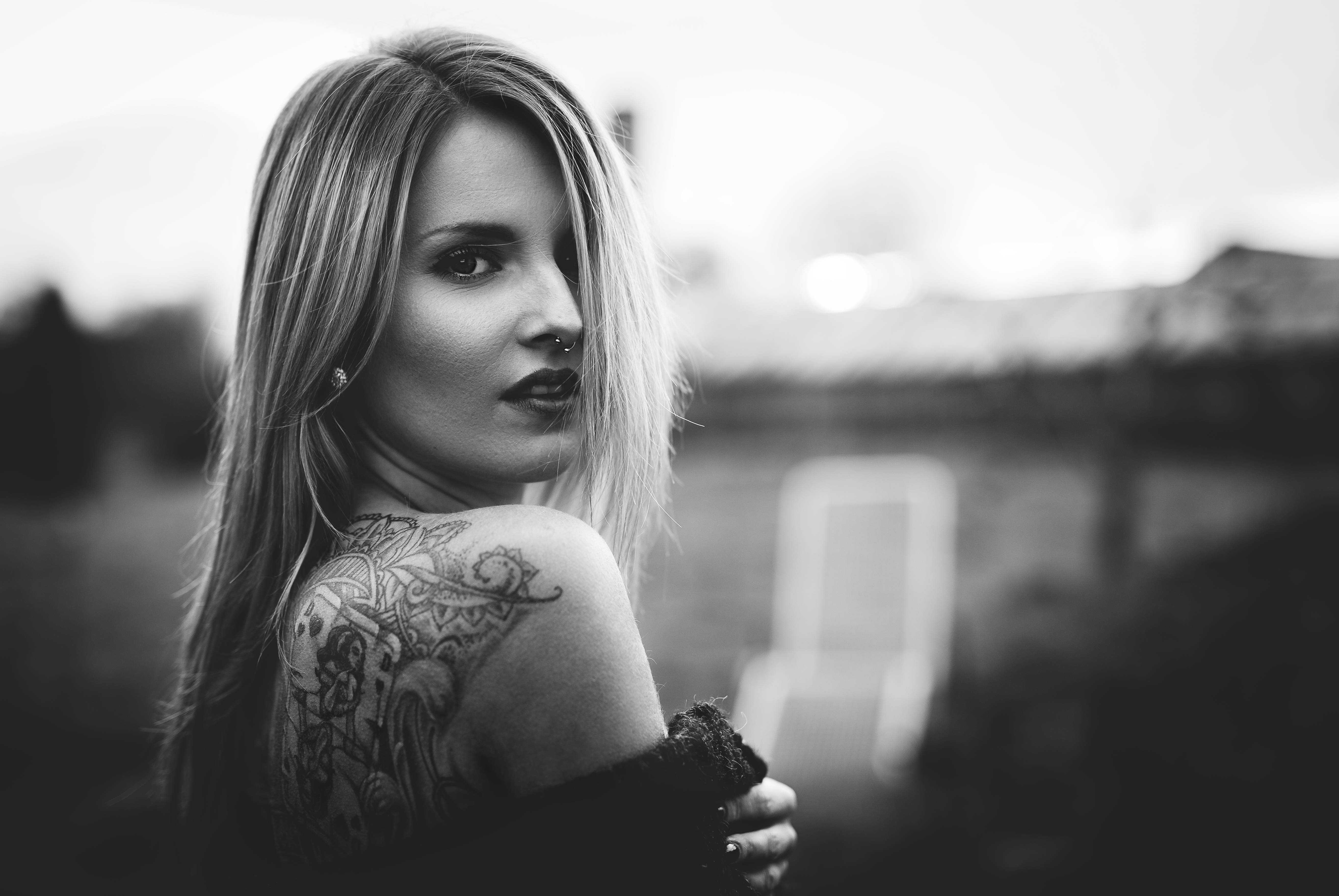 Tattoo 桌布 壁紙 — 一位長金髮、肩上帶有精細刺青的女性，在充滿氛圍的黑白肖像中回頭凝視。