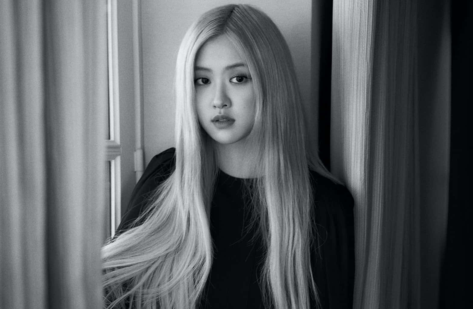 黑色美學 桌布 壁紙 — 一位長金髮女性站在窗簾之間直視鏡頭的黑白肖像。