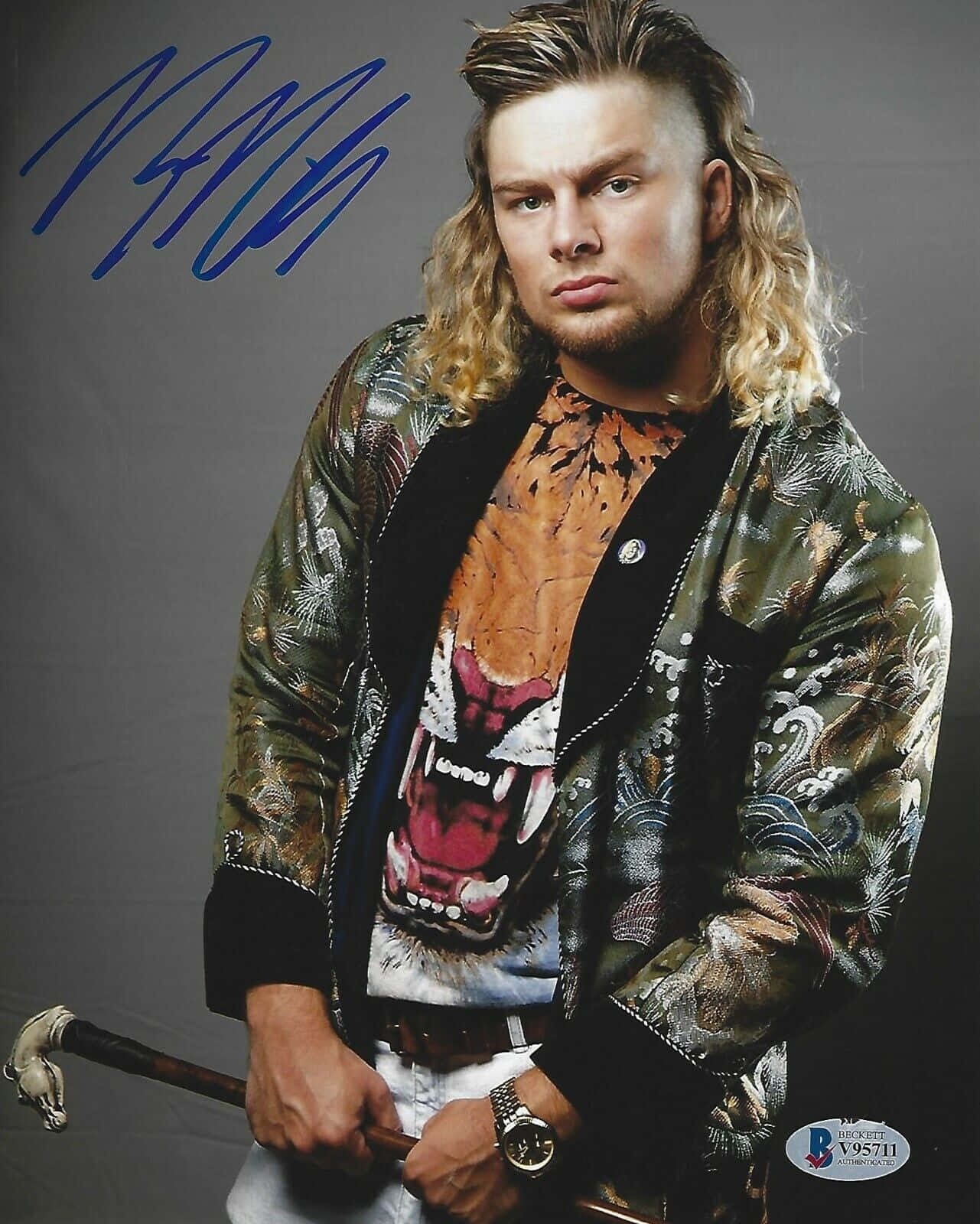 WWE 桌布 壁紙 — 一位長金髮男子穿著圖案外套，內搭老虎印花襯衫，在灰色背景前手持手杖。