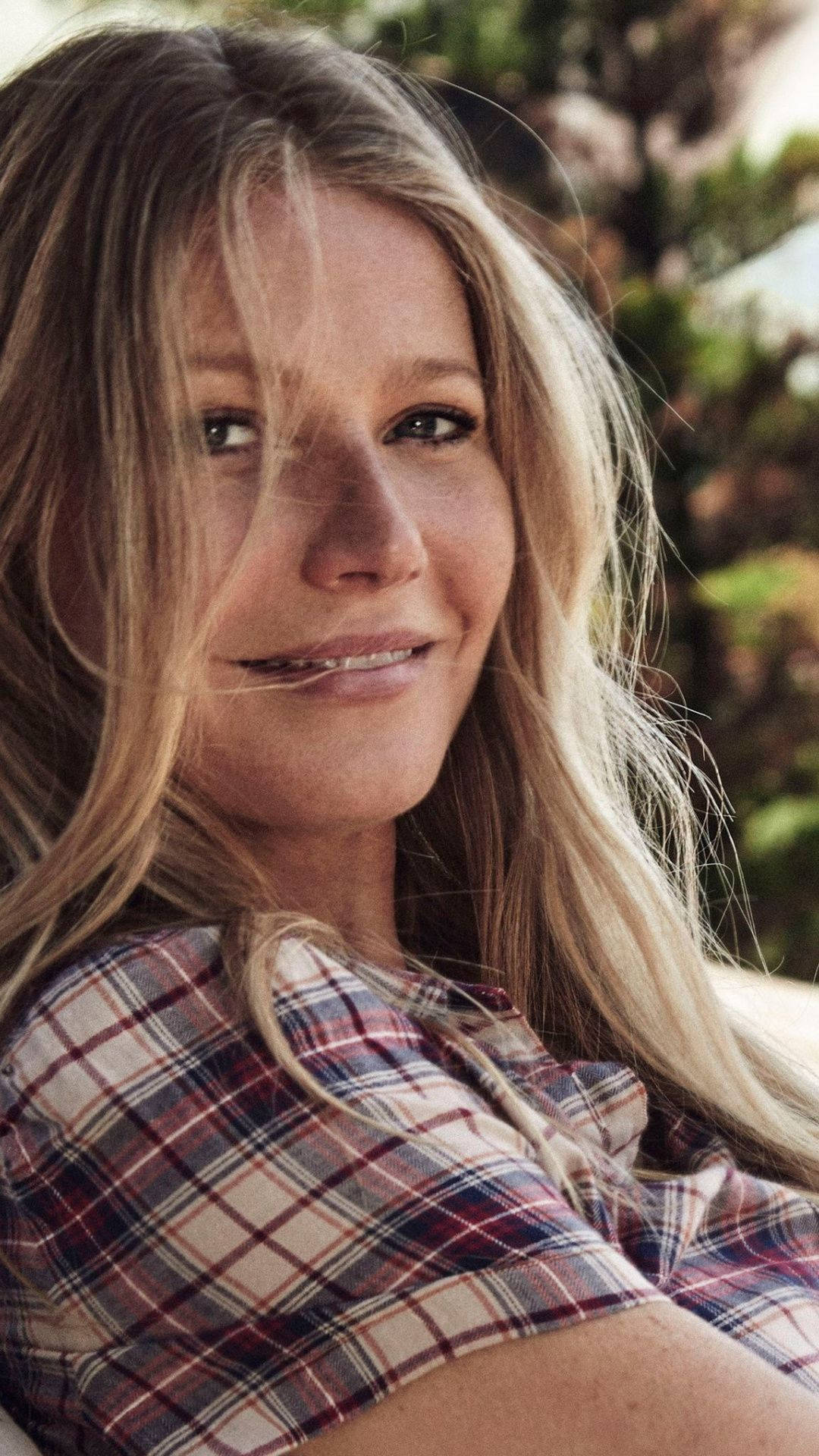 Celebrity 桌布 壁紙 — 一位長金髮的女性在戶外穿著紅、藍、米色格紋襯衫，溫柔地微笑。