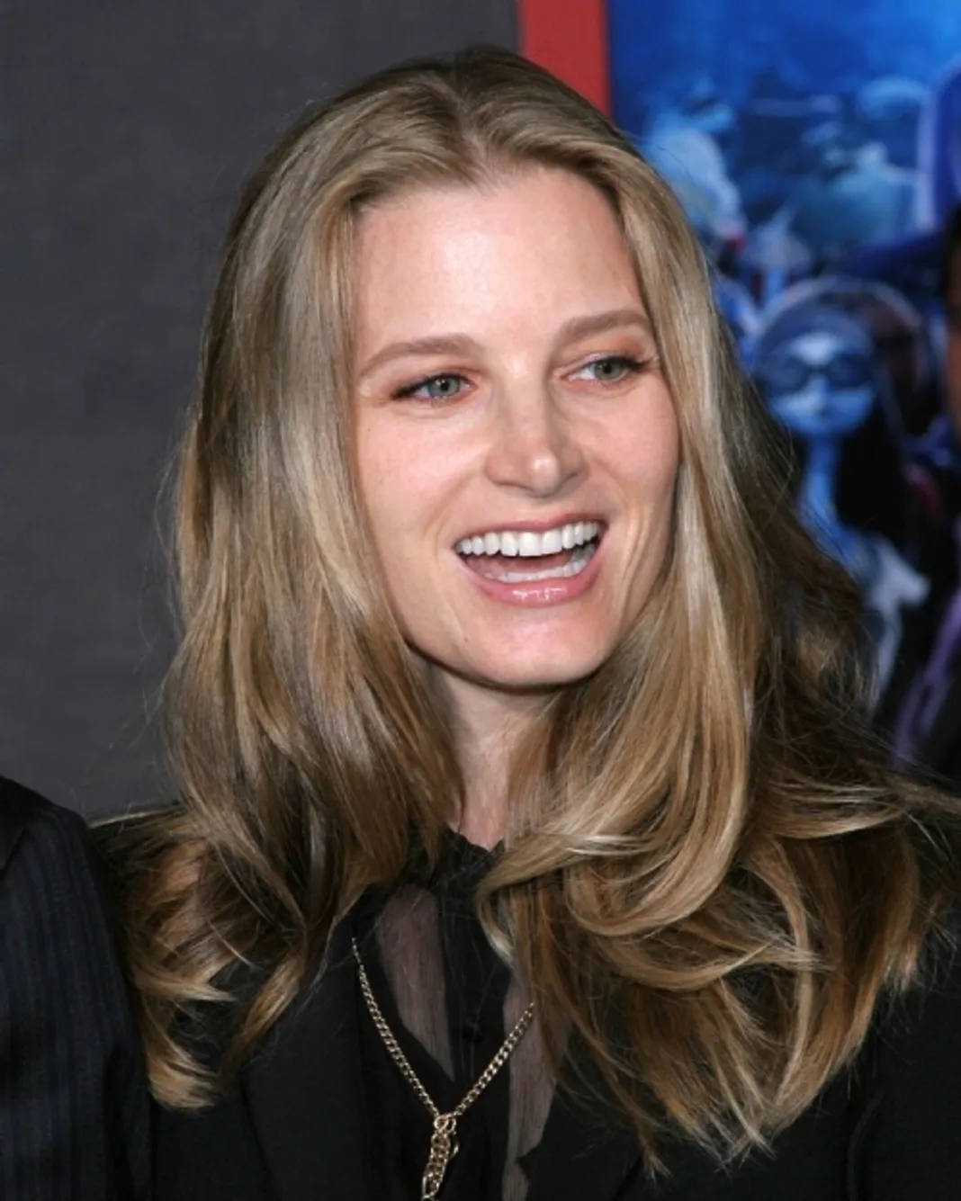 Celebrity 桌布 壁紙 — 一位長金髮的女性穿著黑色服裝和金色項鍊，對著鏡頭燦爛微笑。