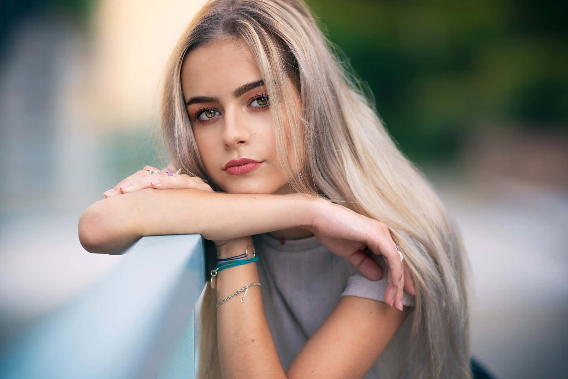 少女風 桌布 壁紙 — 一位長金髮的年輕女子將下巴擱在手臂上，平靜地直視鏡頭。