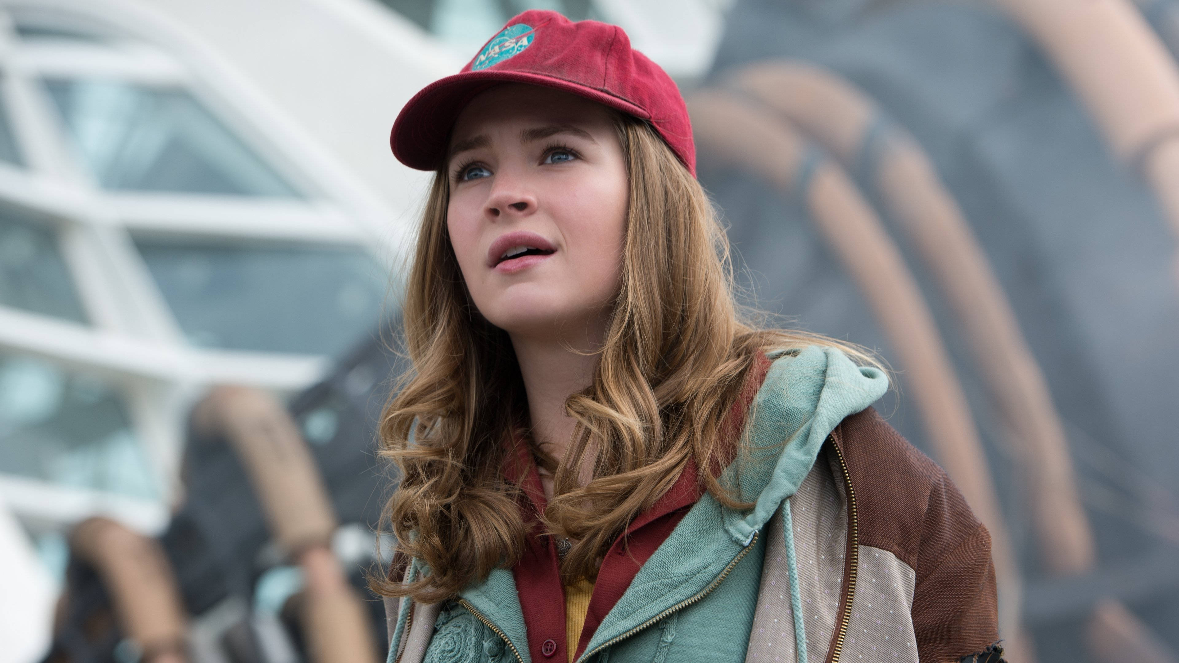 Tomorrowland Movie 桌布 壁紙 — 一位長金髮的年輕女性戴著紅色帽子及多層外套，向上看露出驚訝表情。
