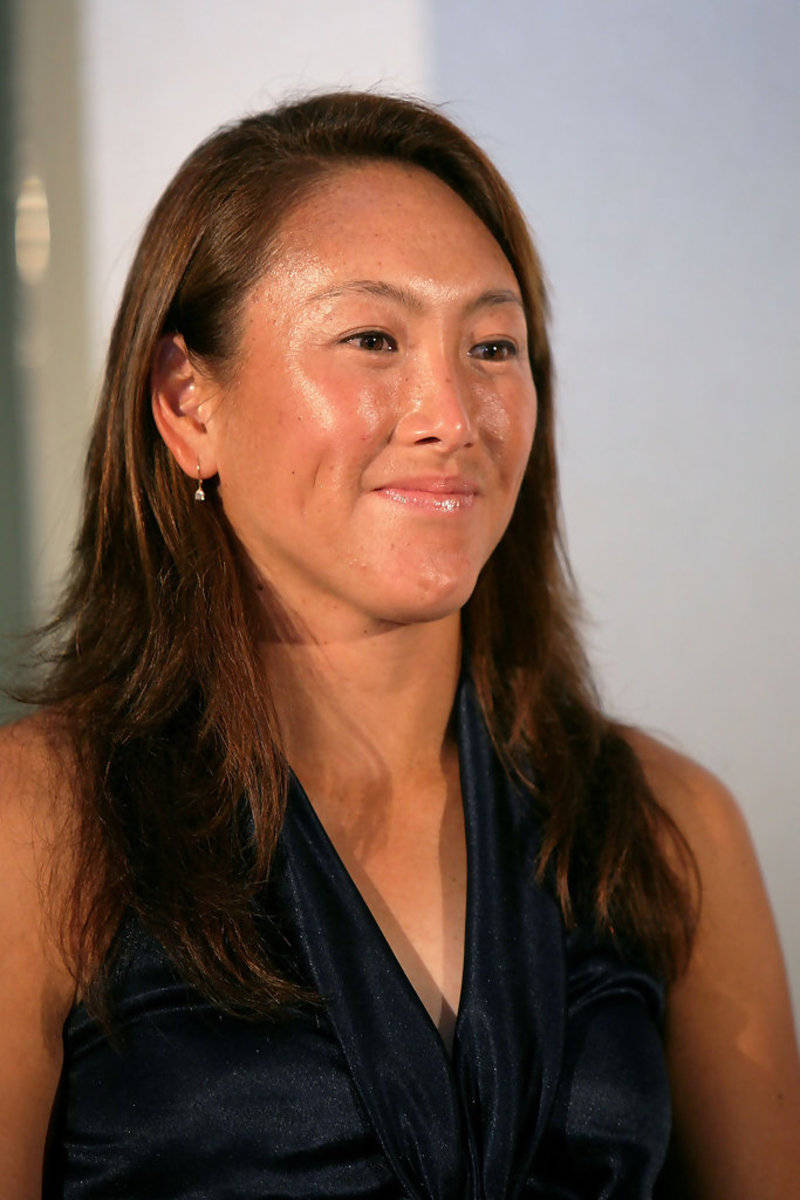 Celebrity 桌布 壁紙 — 一位長長棕色頭髮的女性穿著深藍色緞面上衣，在純色淺色背景前輕柔微笑的特寫肖像。