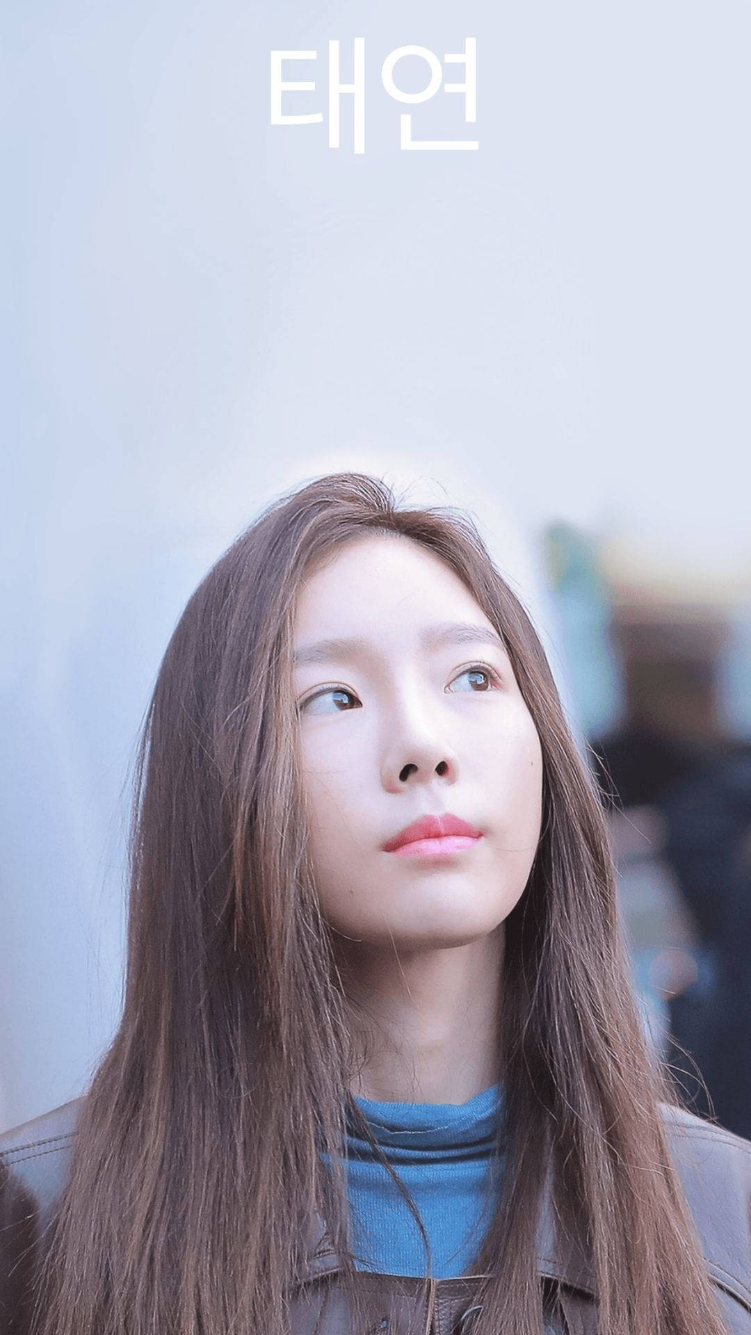 Taeyeon 桌布 壁紙 — 一位長長棕色頭髮的年輕女性，在柔和模糊的背景前，帶著沉思的表情向上凝視。
