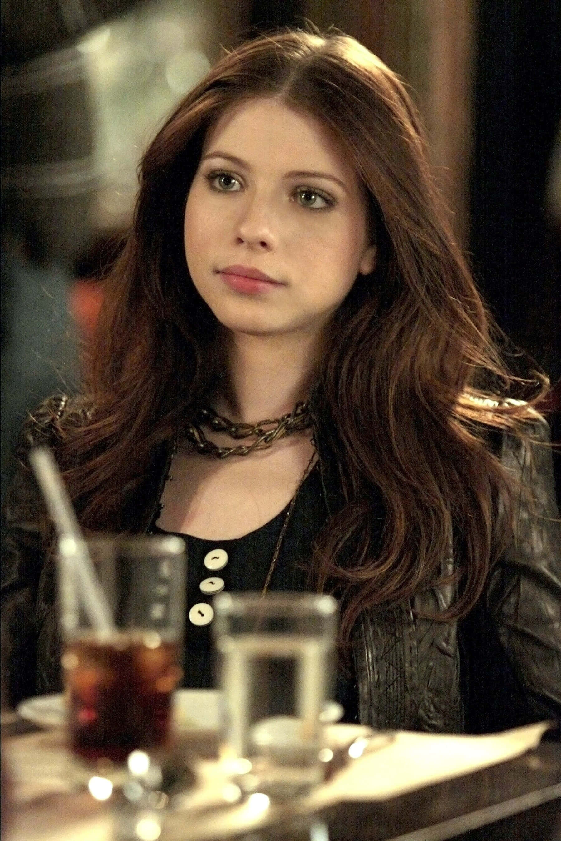michelle trachtenberg 桌布 壁紙 — 一位長長棕色頭髮的年輕女性坐在燈光昏暗的咖啡桌旁，面前有飲料。
