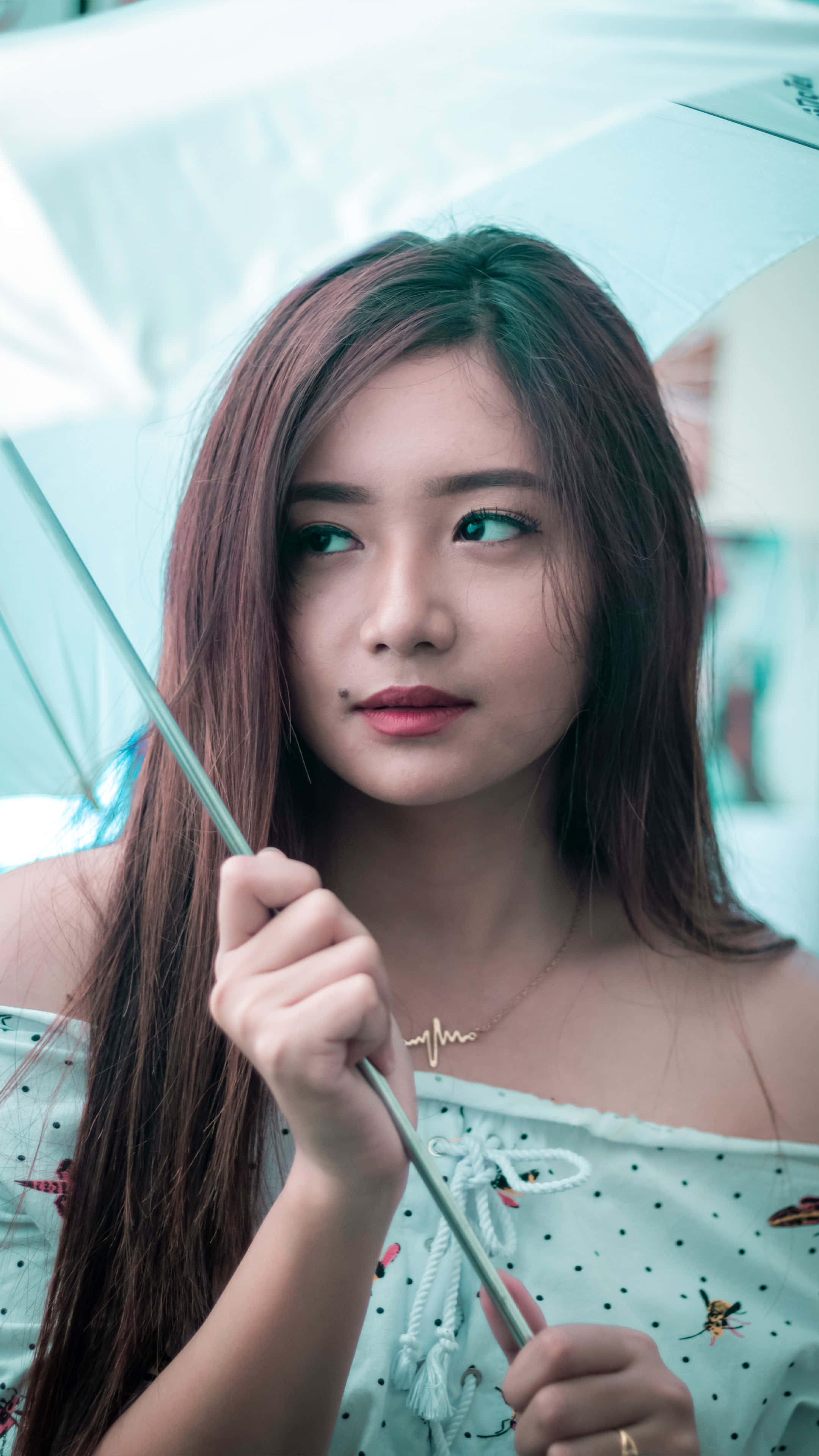 Cute Girl 桌布 壁紙 — 一位長長棕色頭髮的年輕女性手持半透明藍色雨傘，若有所思地望向一旁。
