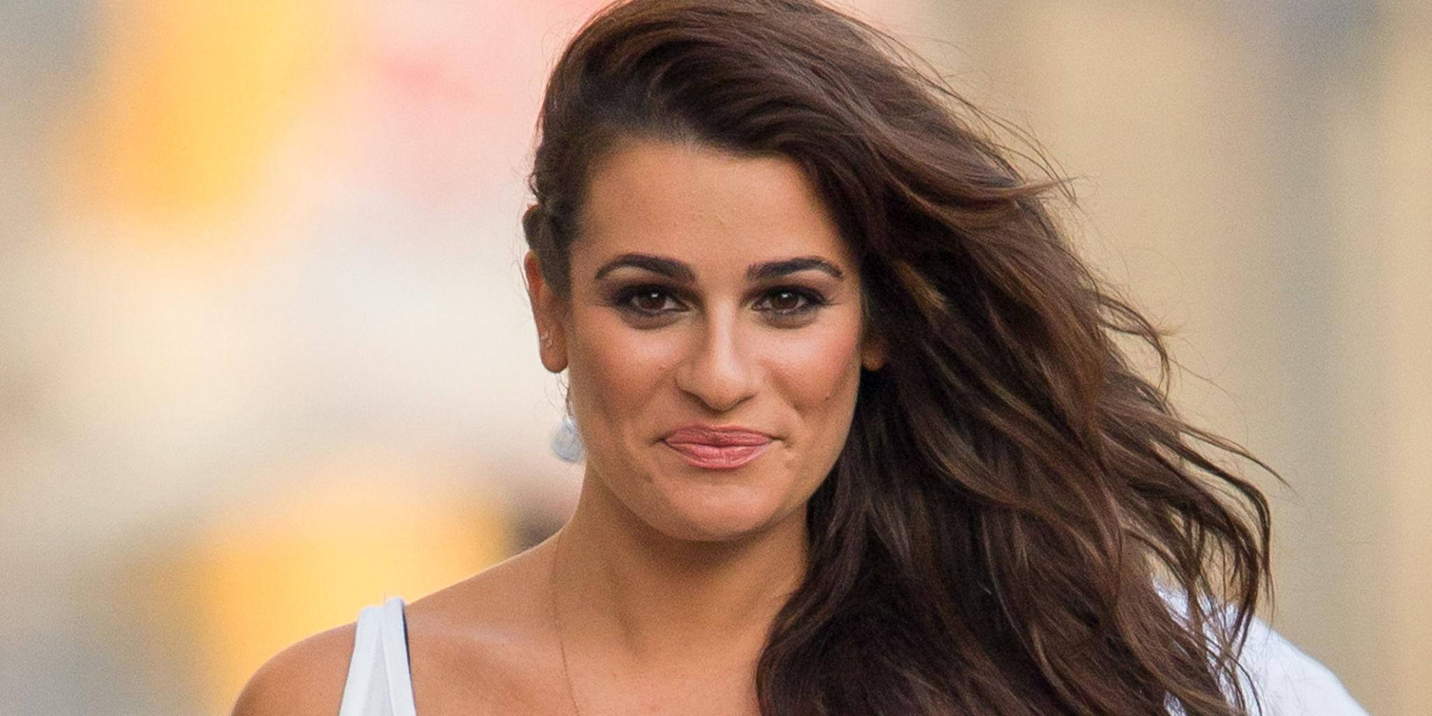 Lea Michele 桌布 壁紙 — 一位長長棕色頭髮隨風飄揚的女性，穿著白色上衣，溫柔地微笑。