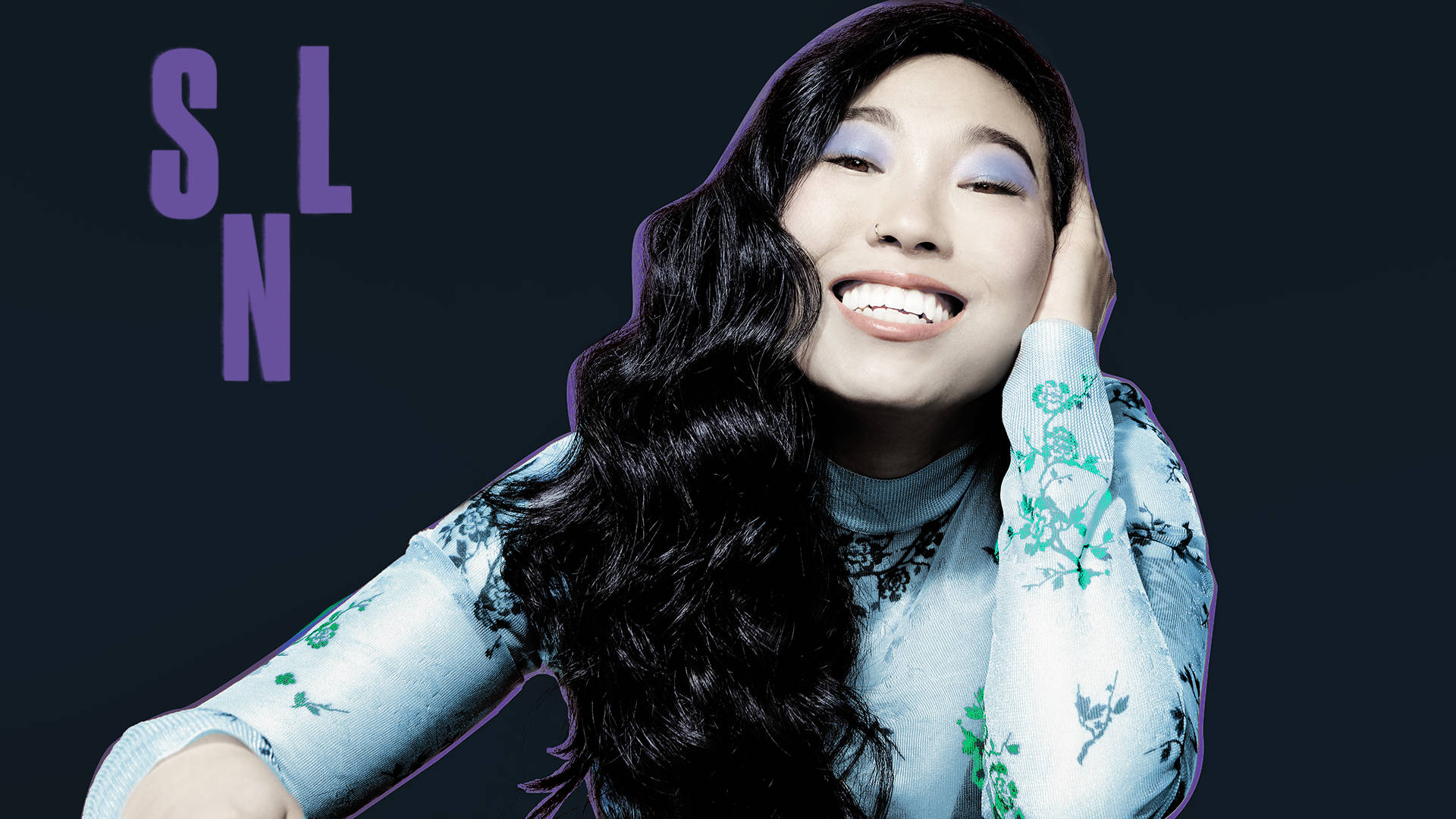 Awkwafina 桌布 壁紙 — 一位長長深色頭髮、塗著紫色眼影的快樂女性，在深色背景襯托下，手托著頭微笑，背景有紫色字樣。