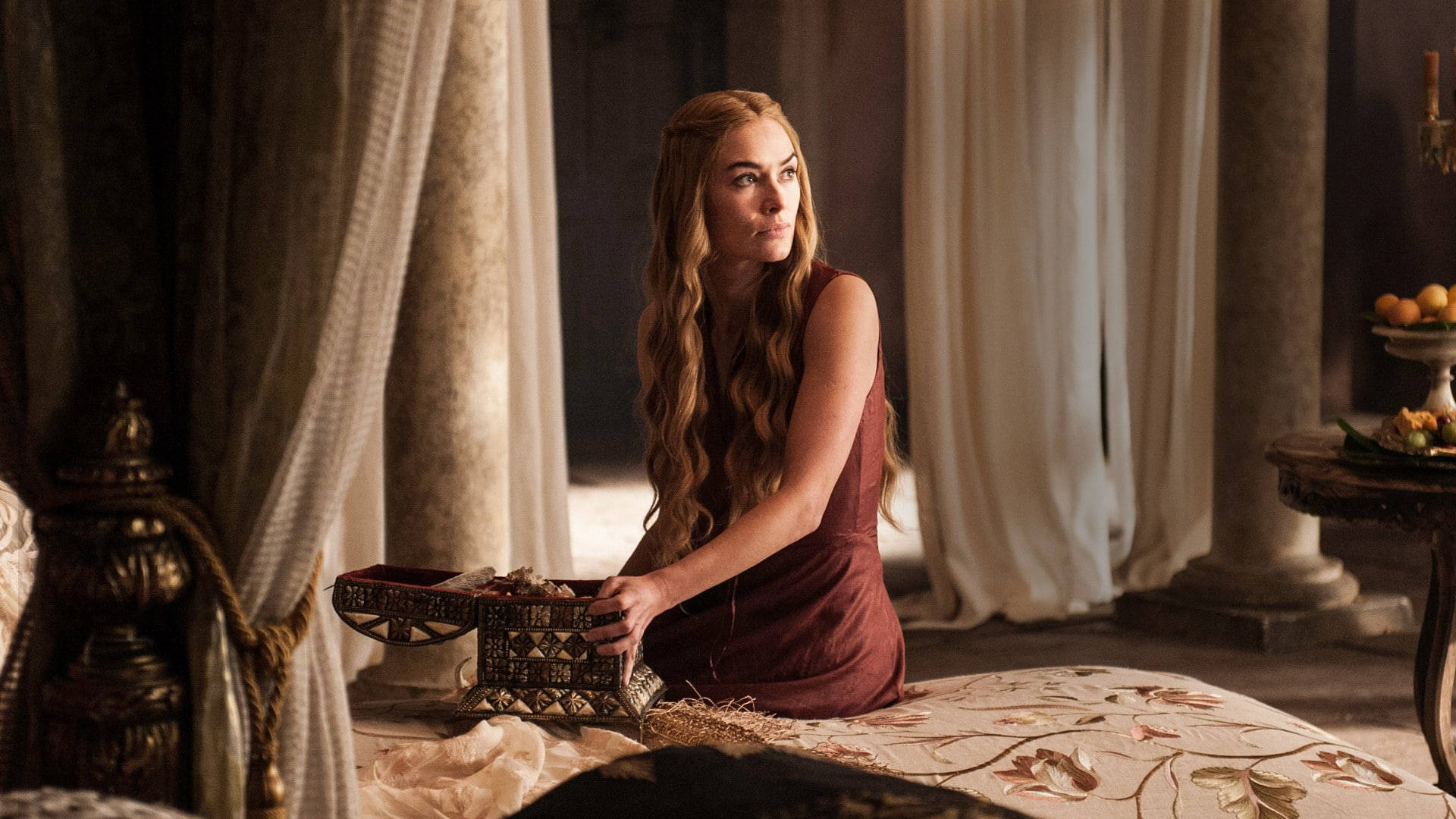 cersei lannister 桌布 壁紙 — 一位長長金髮的女人跪在一張華麗的床上，位於一個掛著厚重窗簾的宏偉石室中。