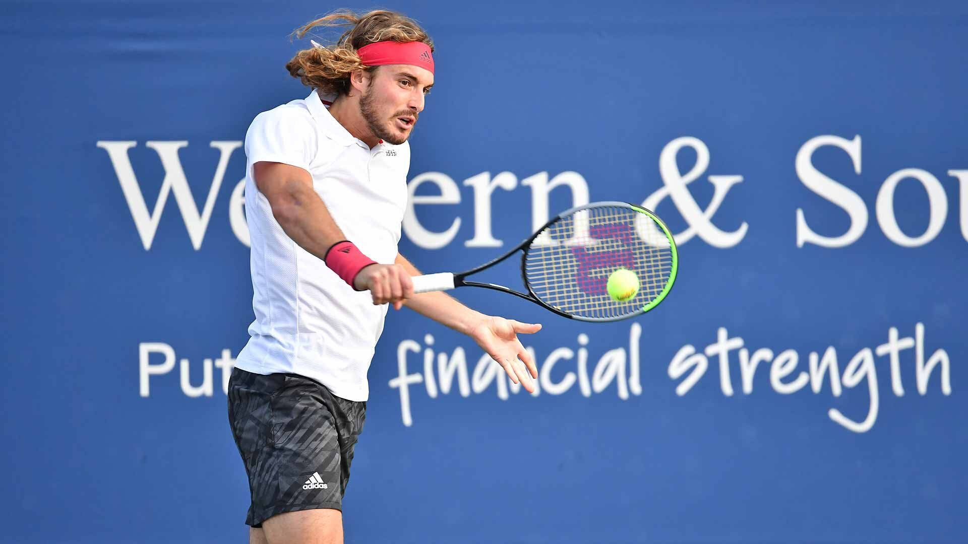網球 桌布 壁紙 — 一位長髮、戴紅色頭帶的男性網球選手揮動球拍，將黃色球擊向帶有白色文字的藍色牆壁。