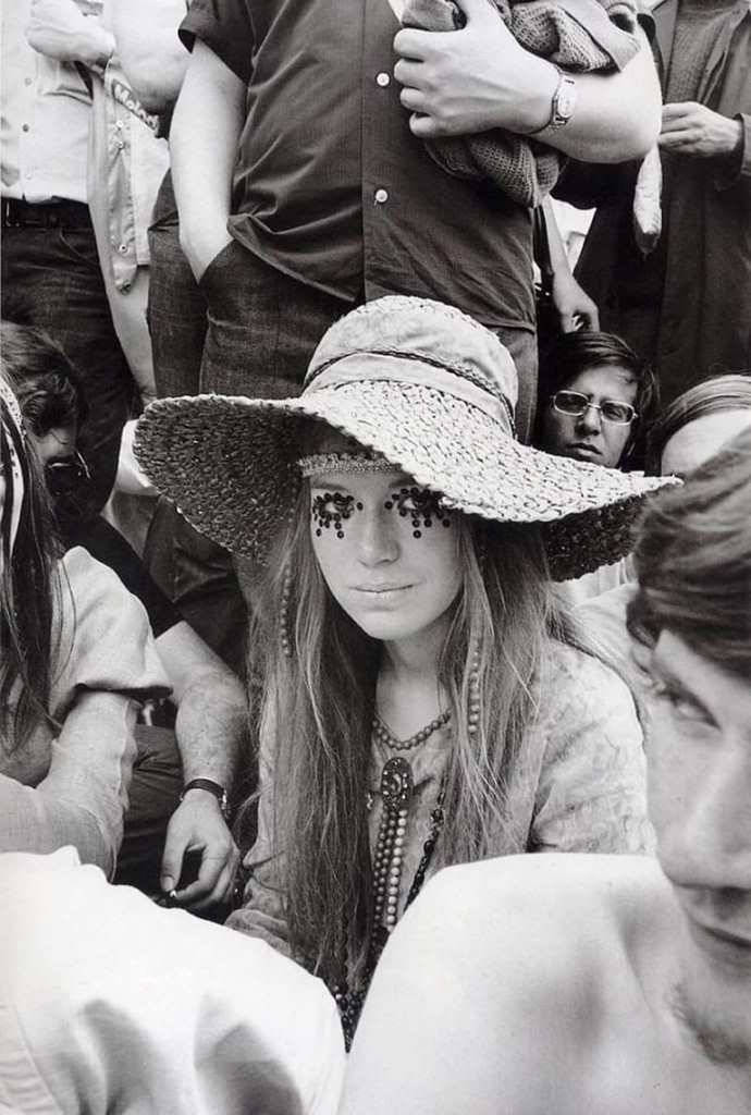 Woodstock 桌布 壁紙 — 一位長髮女子戴著綴有珠子的寬邊帽，在擁擠、粗糙的黑白照片中凝視前方。