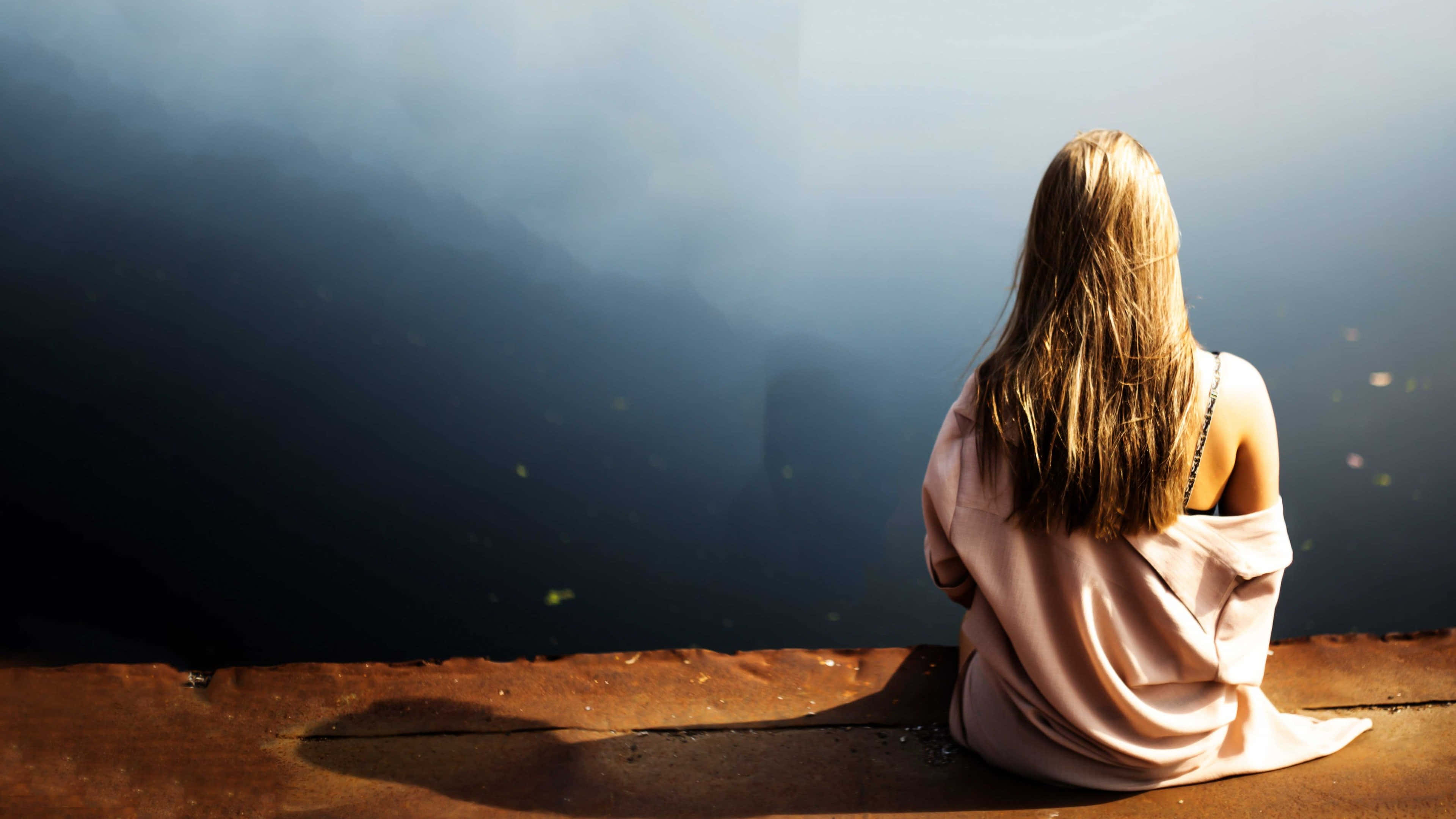 Lonely 桌布 壁紙 — 一位長髮女性獨自坐在生鏽的邊緣，凝視著霧氣瀰漫、陽光普照的深淵。