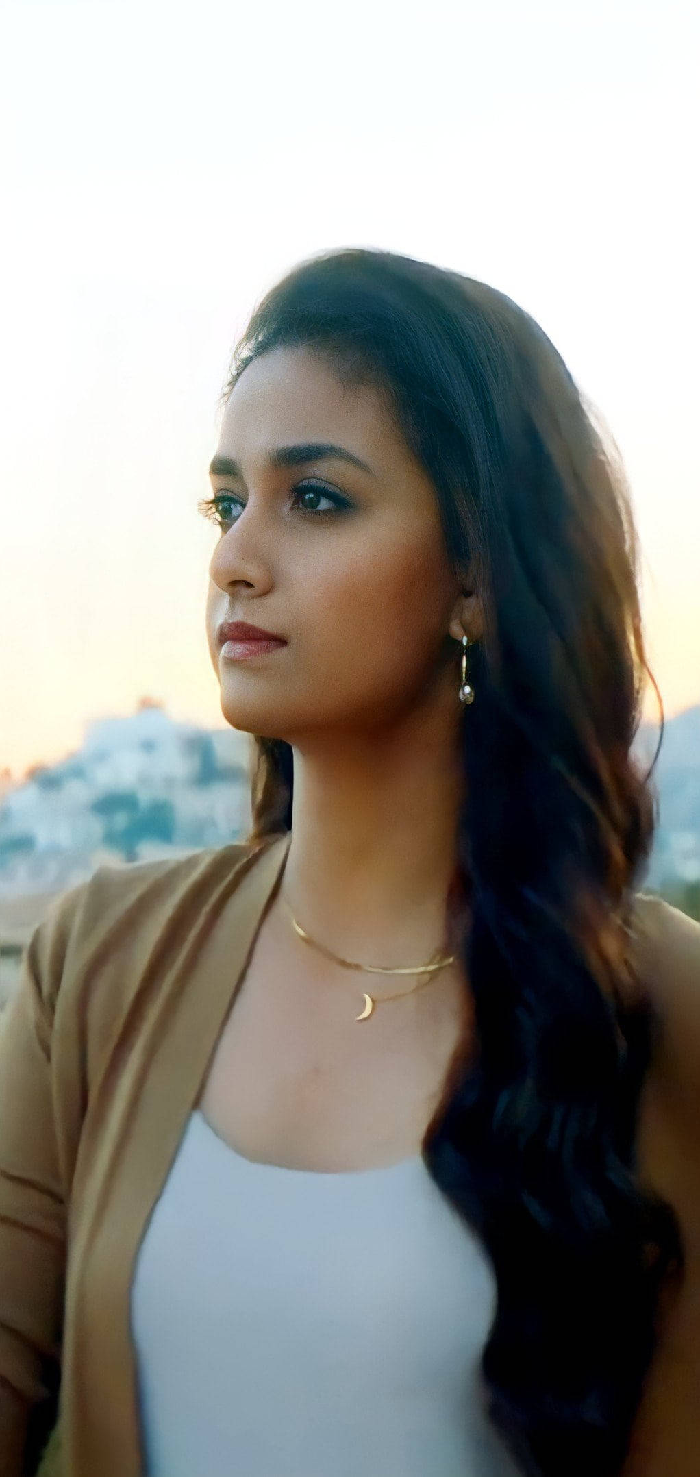 telugu 桌布 壁紙 — 一位長髮深色年輕女子在柔和的金色日落天空下若有所思地向上凝視。