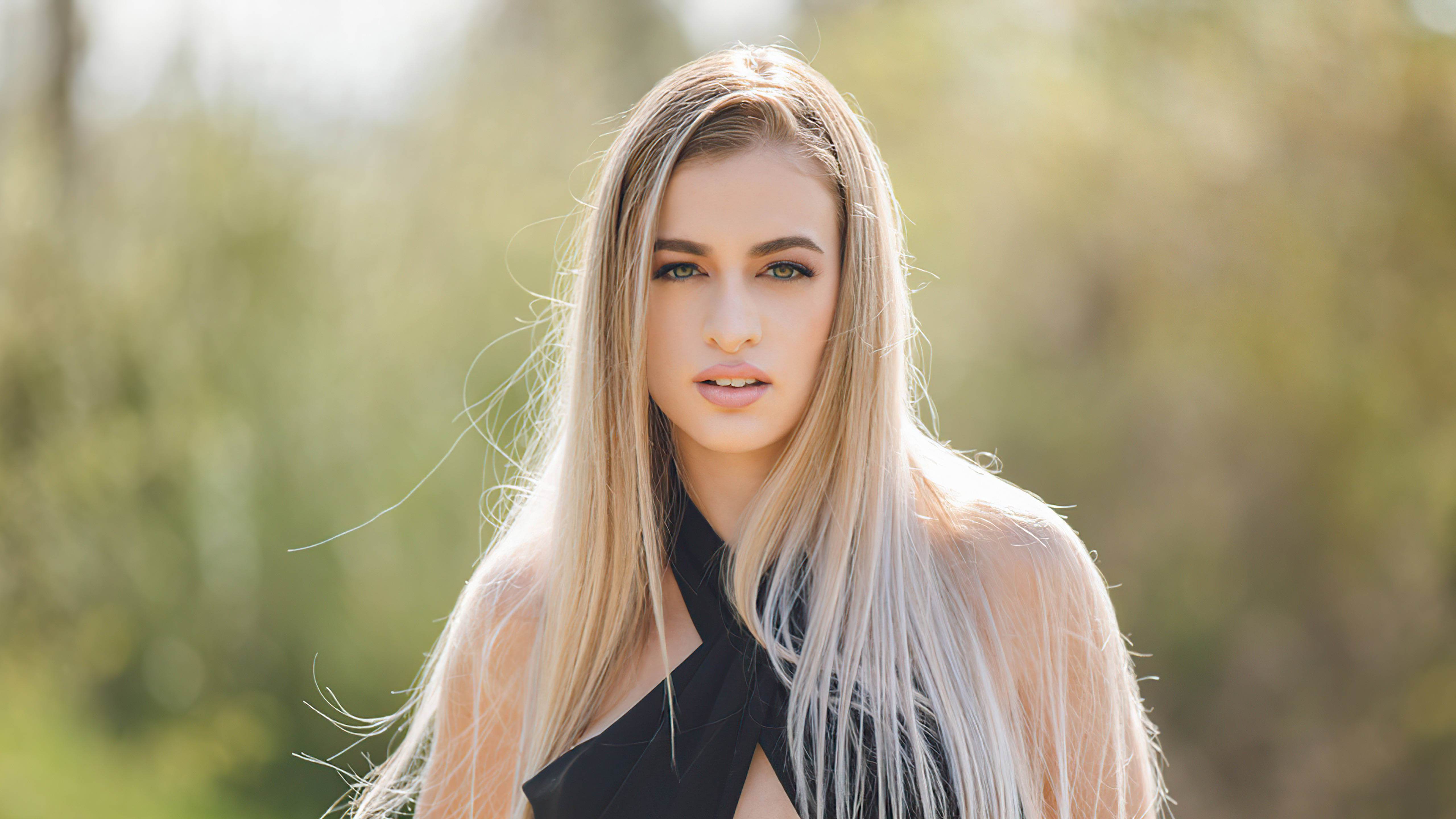 long hair 桌布 壁紙 — 一位長髮金髮女性在柔和自然光下，以模糊的綠色背景為襯，直視鏡頭。