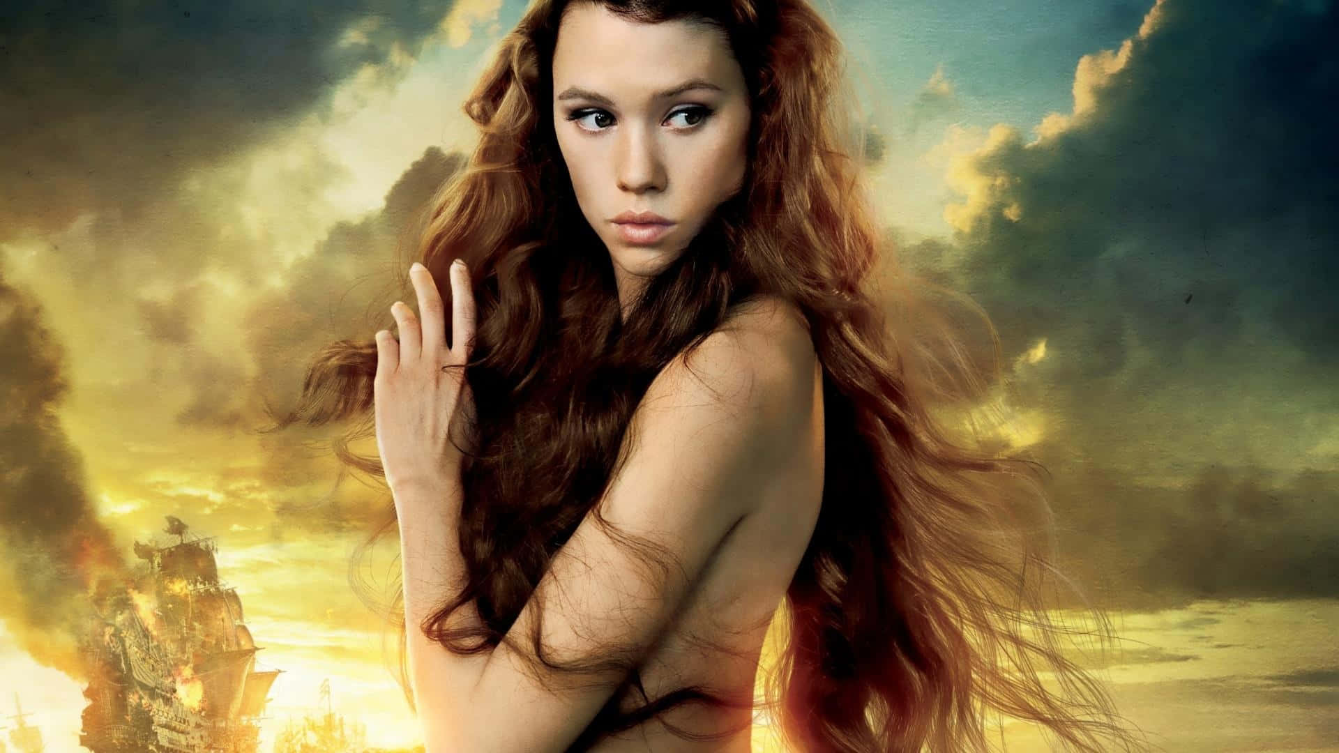 Astrid Berges Frisbey 桌布 壁紙 — 一位長髮飄逸的女性站在戲劇性的天空背景下，背景中有一艘燃燒的船。