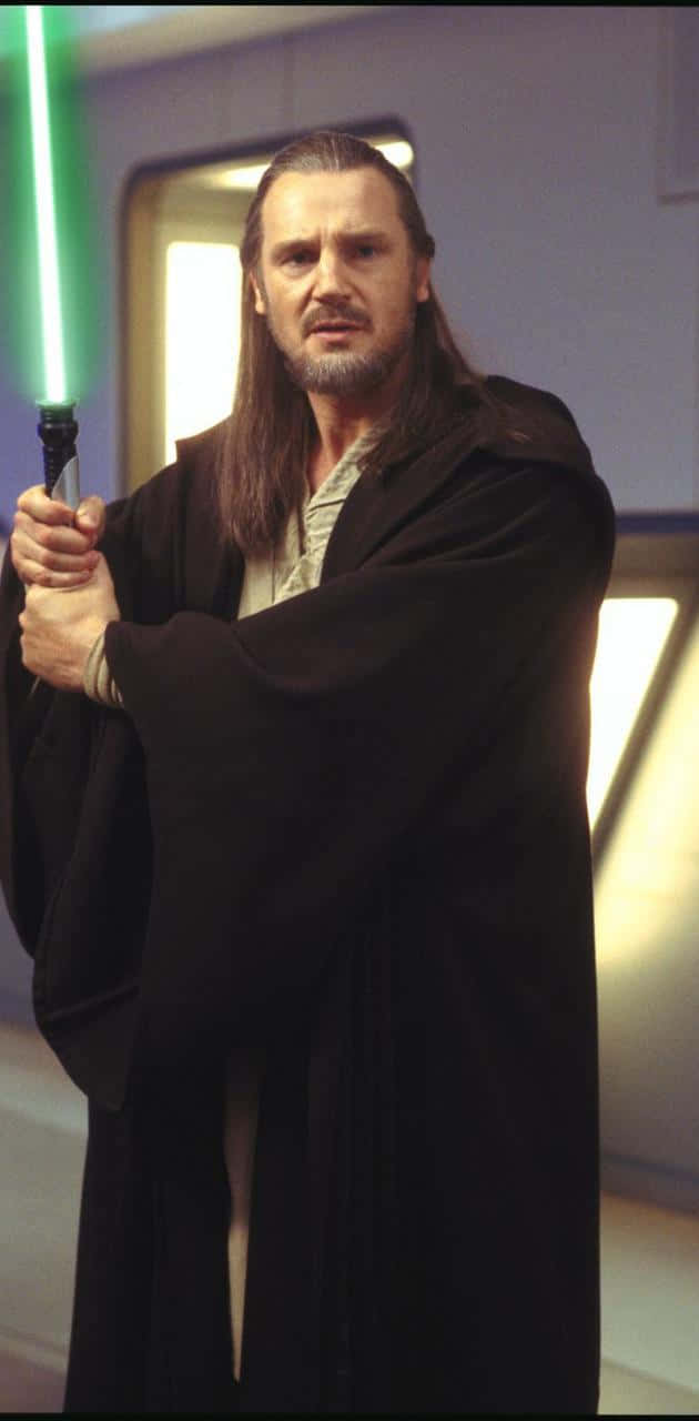 Qui-gon Jinn 桌布 壁紙 — 一位長髮鬍鬚的絕地大師在未來主義走廊中手持發光的綠色光劍。