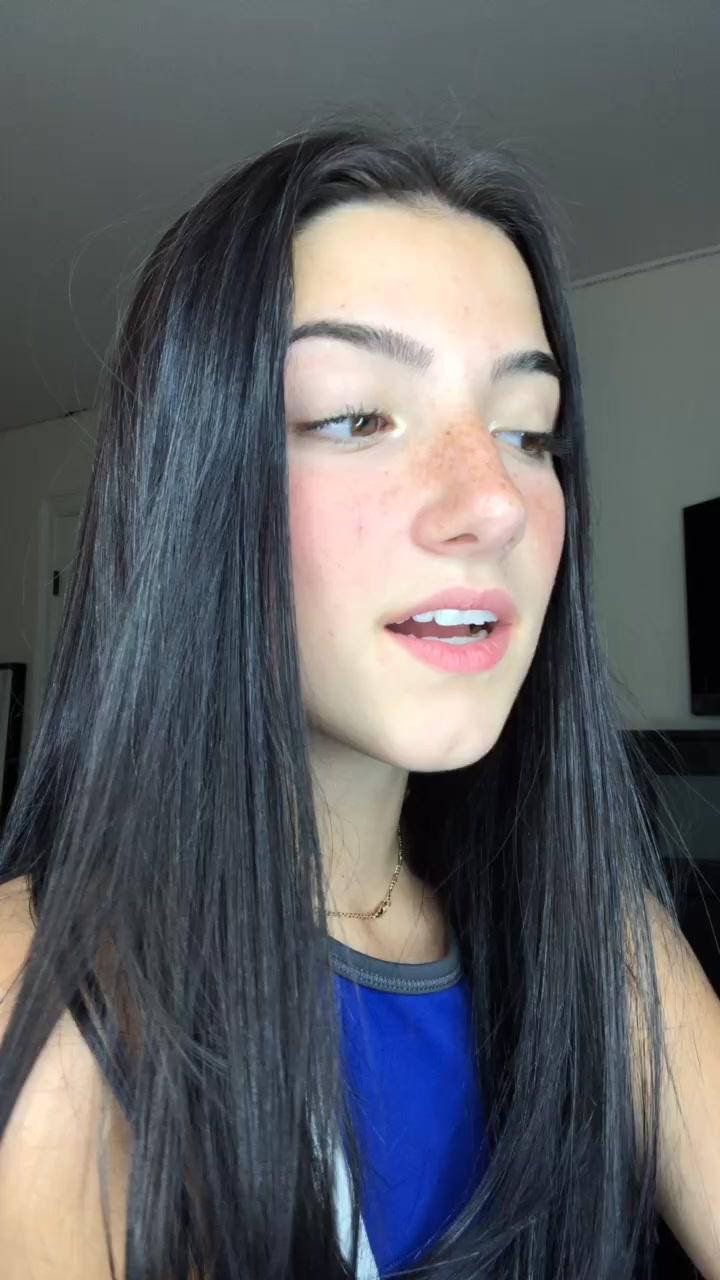 Charli Damelio 桌布 壁紙 — 一位長黑髮、有雀斑的年輕女性在休閒的室內環境中看向鏡頭外。