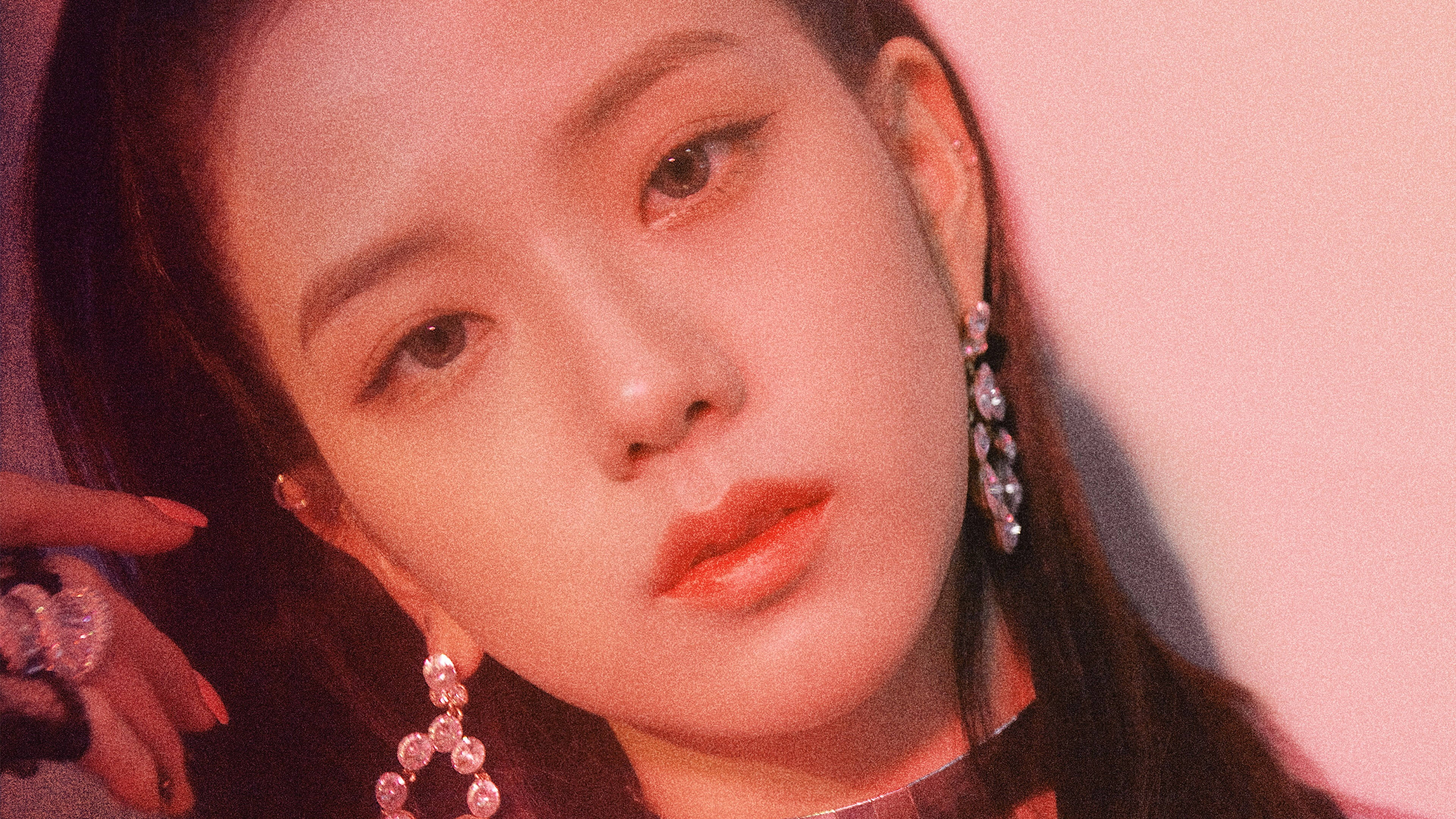 Blackpink Aesthetic 桌布 壁紙 — 一位長黑髮女性在柔和粉紅燈光下戴著閃亮垂墜耳環的特寫肖像。