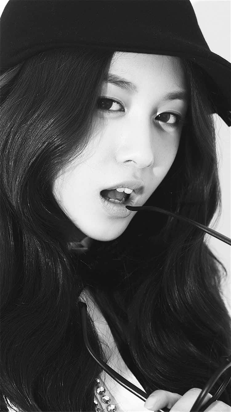 Singer 桌布 壁紙 — 一位長黑髮女性戴著帽子，手持太陽眼鏡靠近嘴巴的黑白肖像。