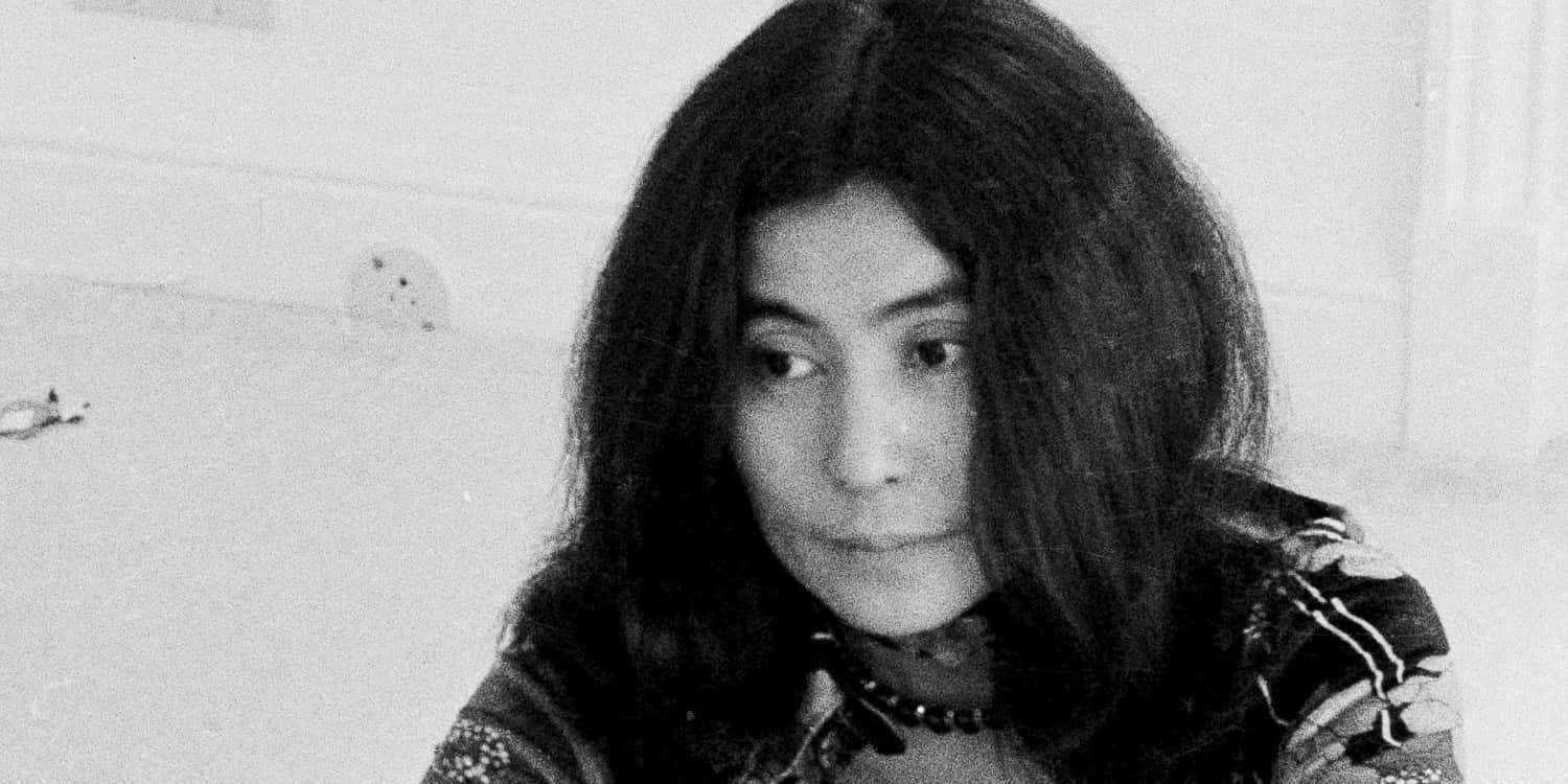 寬螢幕動態圖片 桌布 壁紙 — 一位長黑髮女性面無表情直視鏡頭的黑白肖像照。