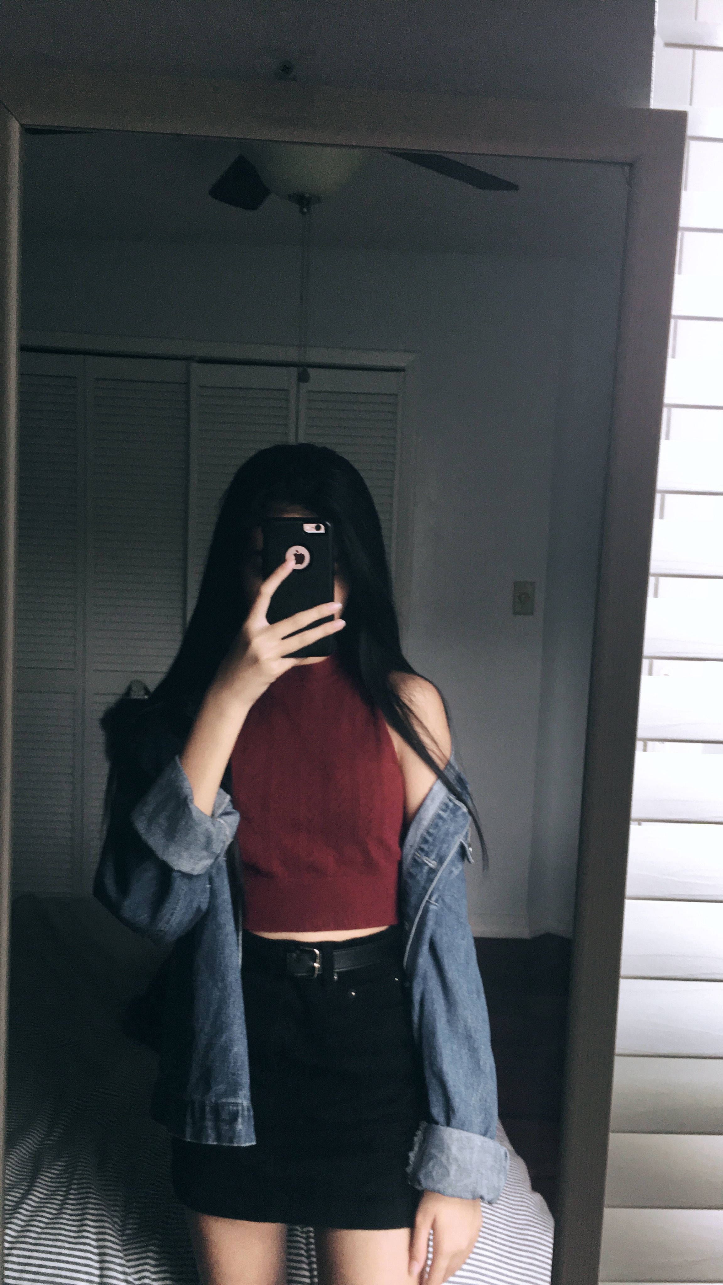 Aesthetic Profile 桌布 壁紙 — 一位長黑髮的人在昏暗的臥室裡穿著紅色露臍上衣和牛仔外套對著鏡子自拍。