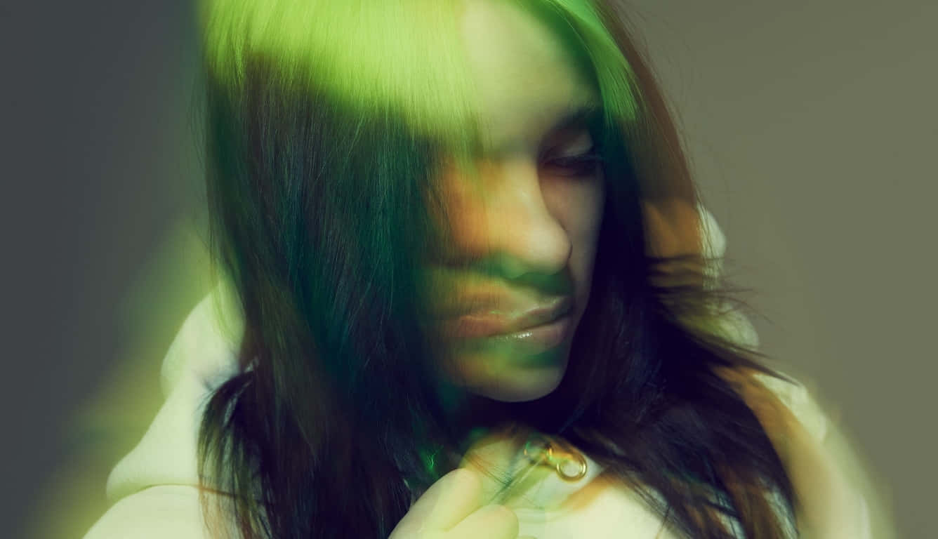 Billie Eilish Laptop 桌布 壁紙 — 一位長黑髮的人沐浴在充滿活力的綠光中，營造出柔和焦點和發光高光的夢幻、陰鬱肖像。