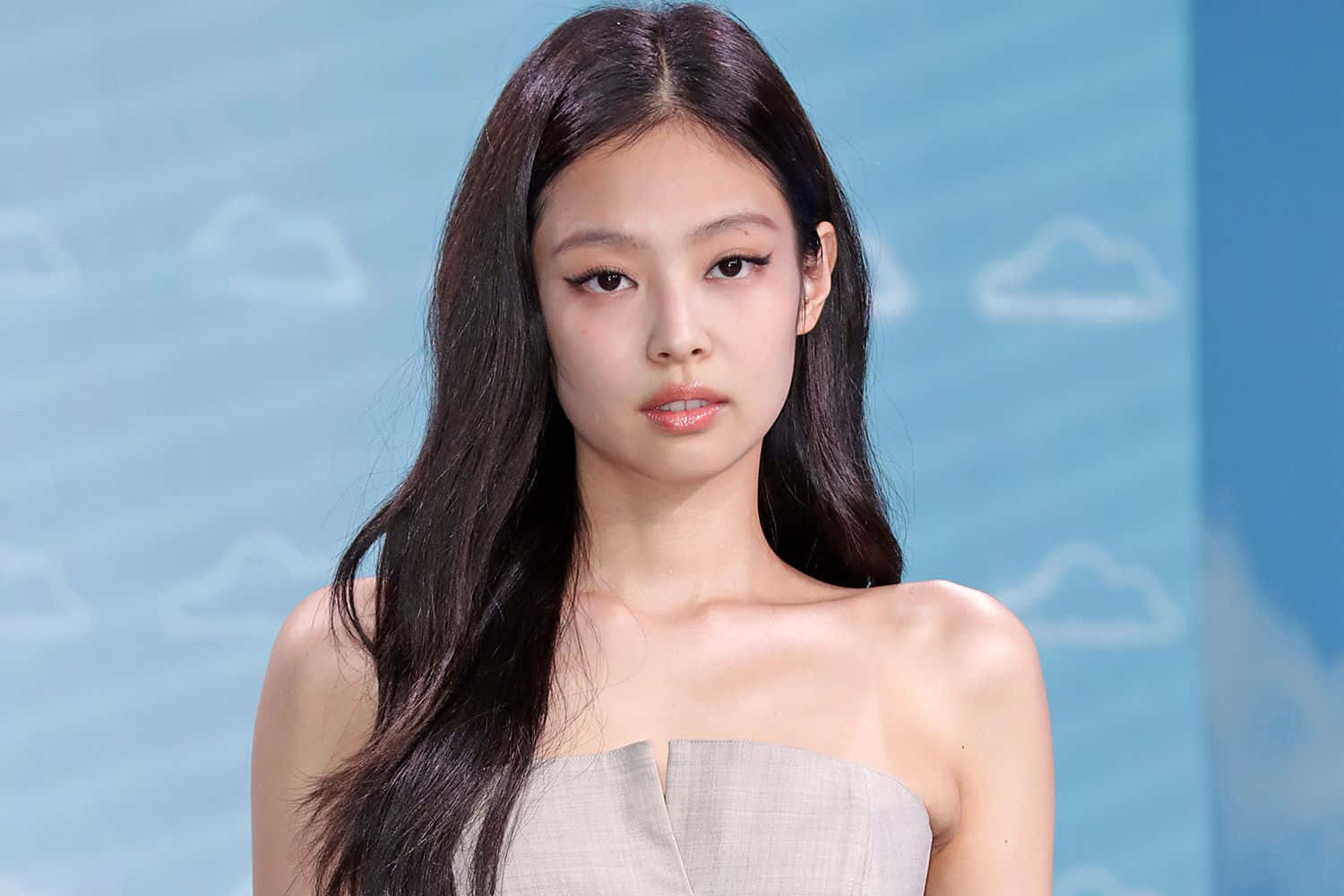 BLACKPINK 桌布 壁紙 — 一位長黑髮的優雅女性，穿著無肩帶米色連衣裙，背景是帶有白雲的柔和藍天。