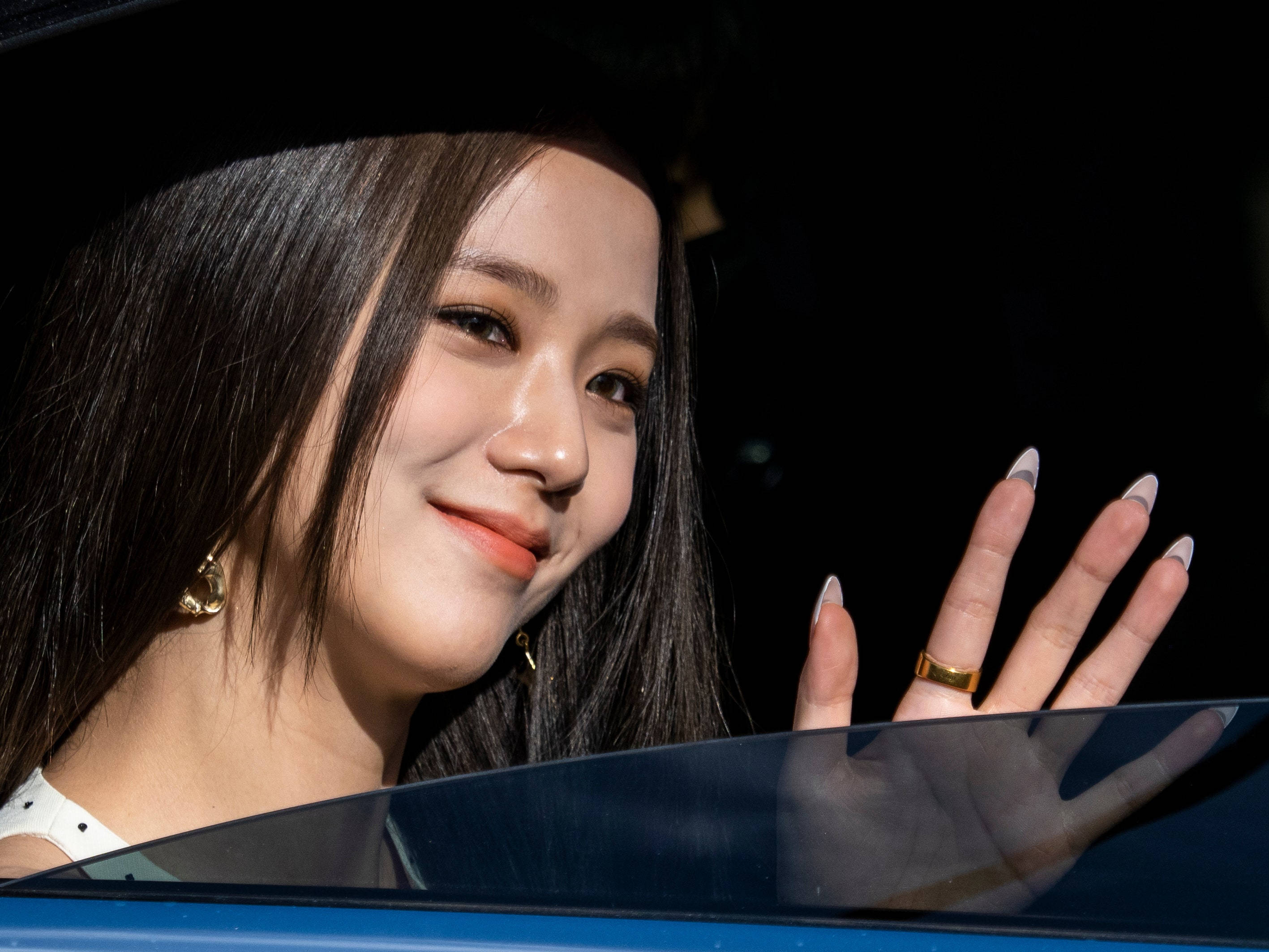 Smile 桌布 壁紙 — 一位長黑髮的女士面帶微笑，戴著金耳環和戒指，從車窗揮手。