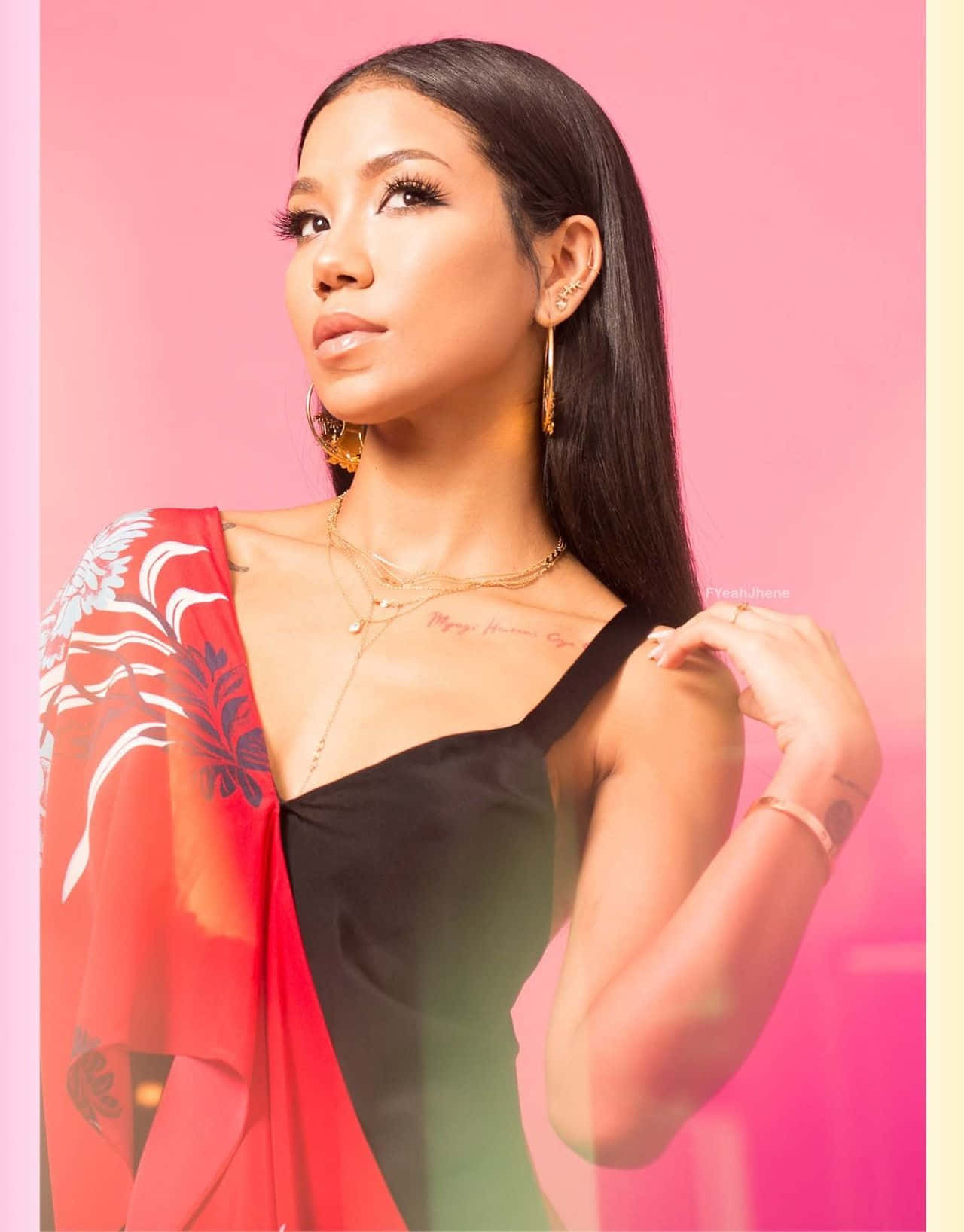 jhene aiko 桌布 壁紙 — 一位長黑髮的女性，在充滿活力的粉紅色背景前，穿著黑色上衣和紅色花卉披肩。