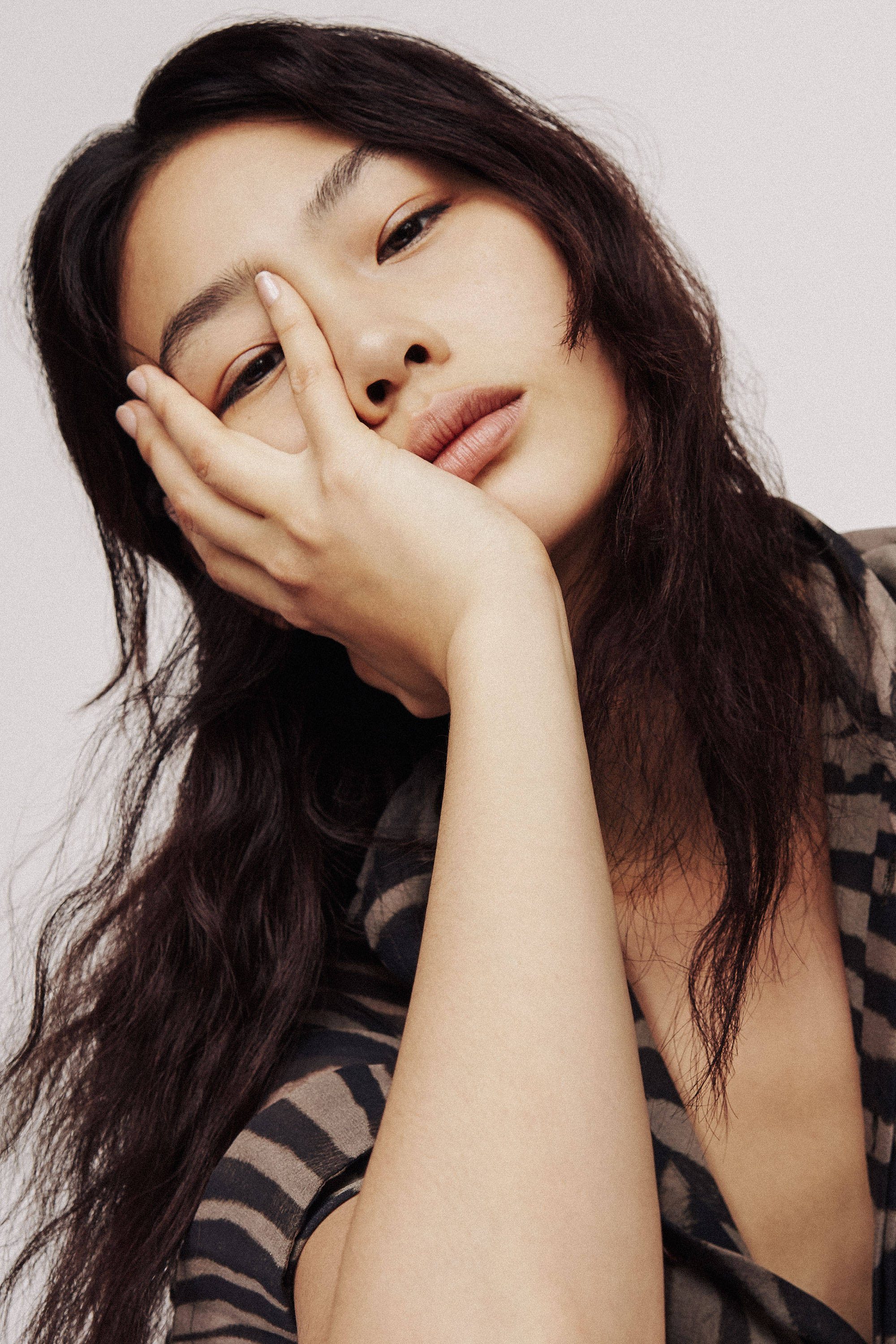 Hoyeon 桌布 壁紙 — 一位長黑髮的女性在柔和的工作室肖像中將手放在眼睛上。