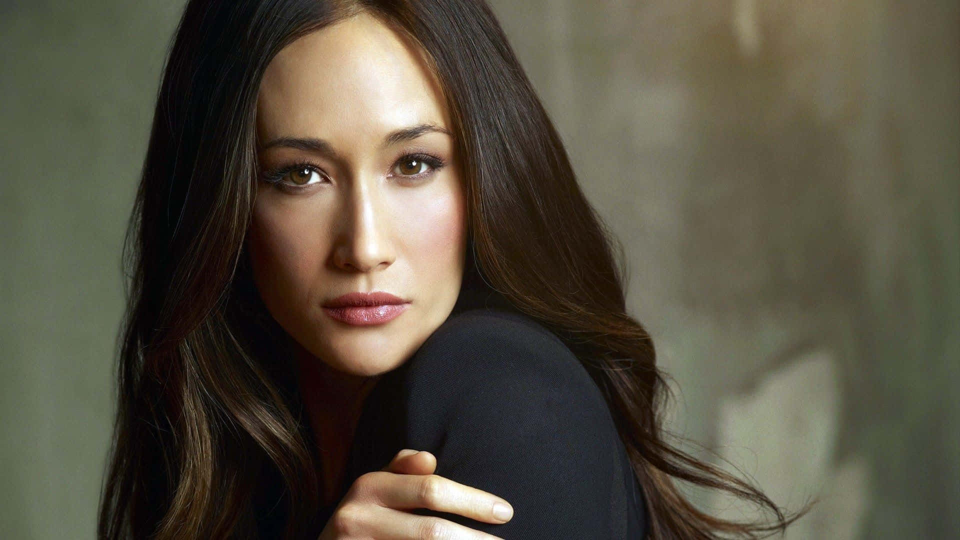 maggie q 桌布 壁紙 — 一位長黑髮的女性在柔和的灰色背景前溫柔地凝視著相機。