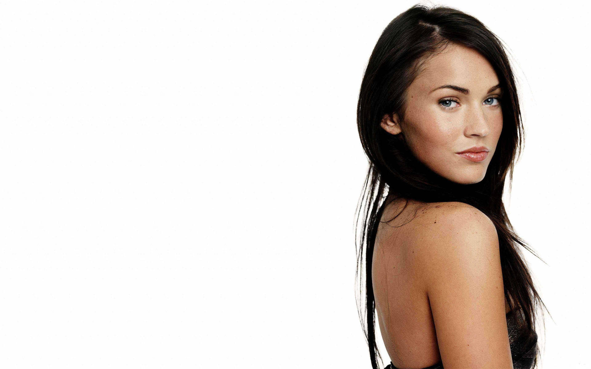 Megan Fox HD 桌布 壁紙 — 一位長黑髮的女性在純白背景下轉頭越過肩膀。