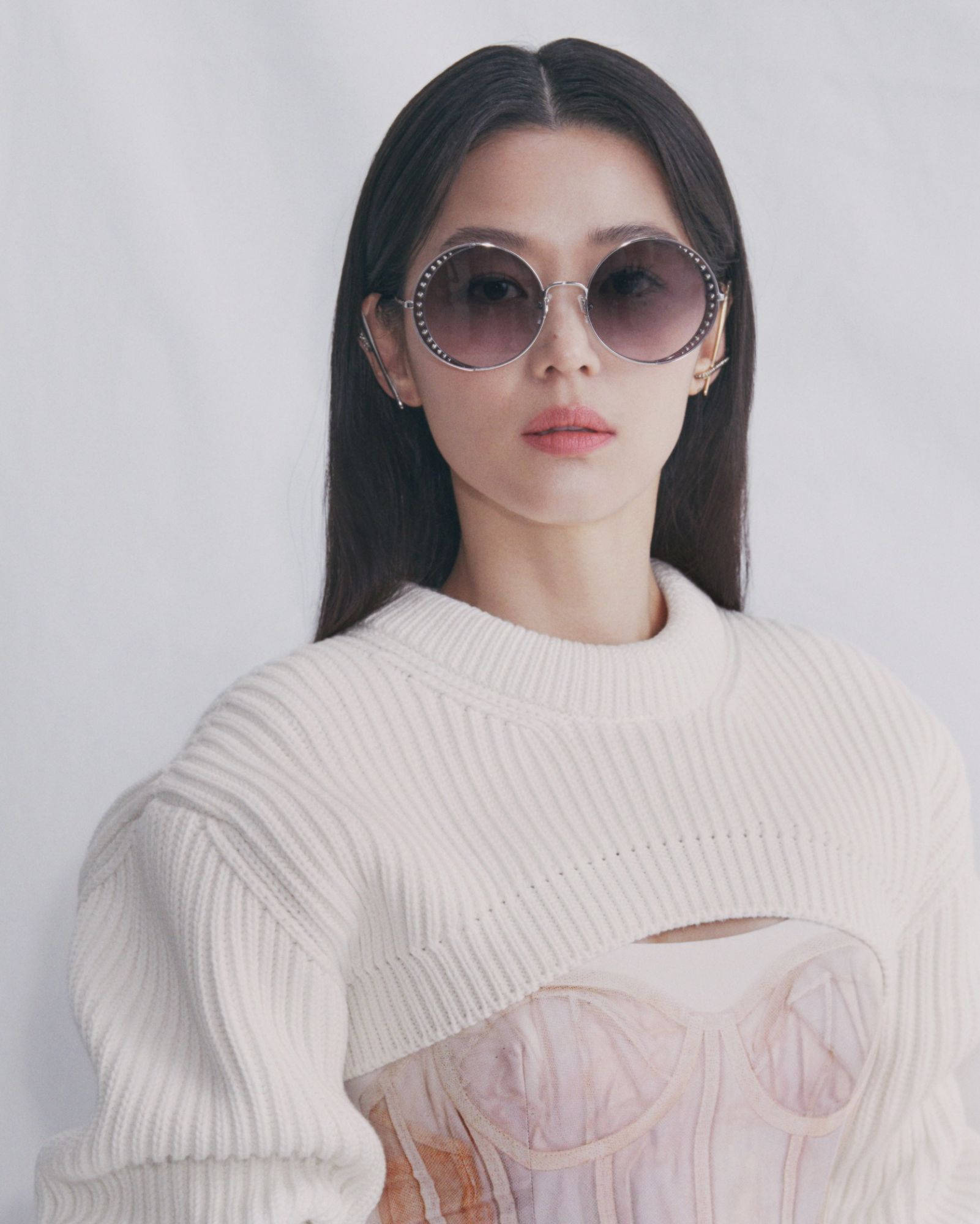 Jun Ji Hyun 桌布 壁紙 — 一位長黑髮的女性戴著超大圓形太陽眼鏡，穿著奶油色羅紋毛衣，內搭透視緊身衣，背景為純白色。