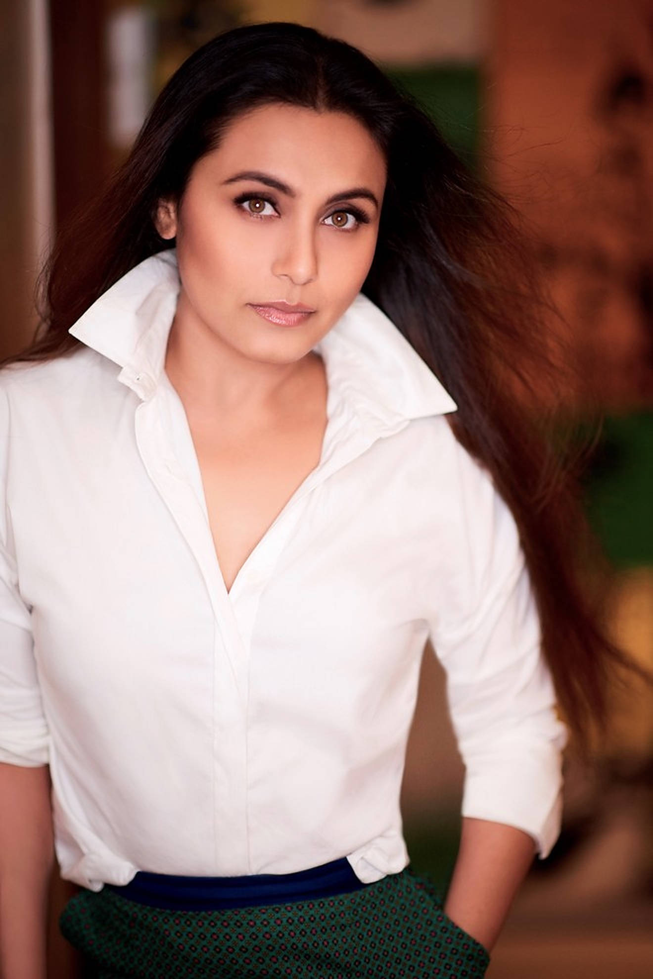 Rani Mukerji 桌布 壁紙 — 一位長黑髮的女性穿著白色襯衫和綠色圖案裙子，直視鏡頭，表情柔和。