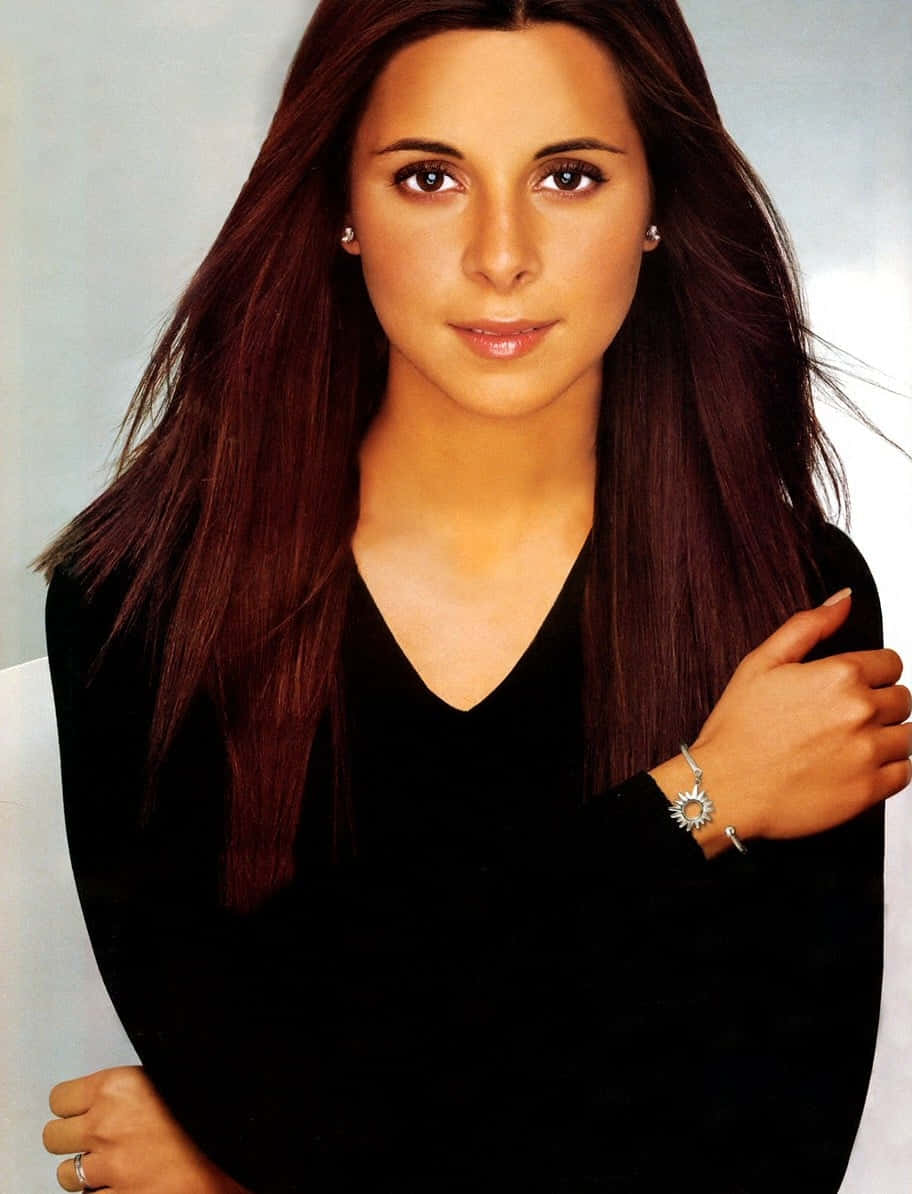 Jamie Lynn Sigler 桌布 壁紙 — 一位長黑髮的女性穿著黑色上衣和銀色首飾，背景是柔和的灰色。
