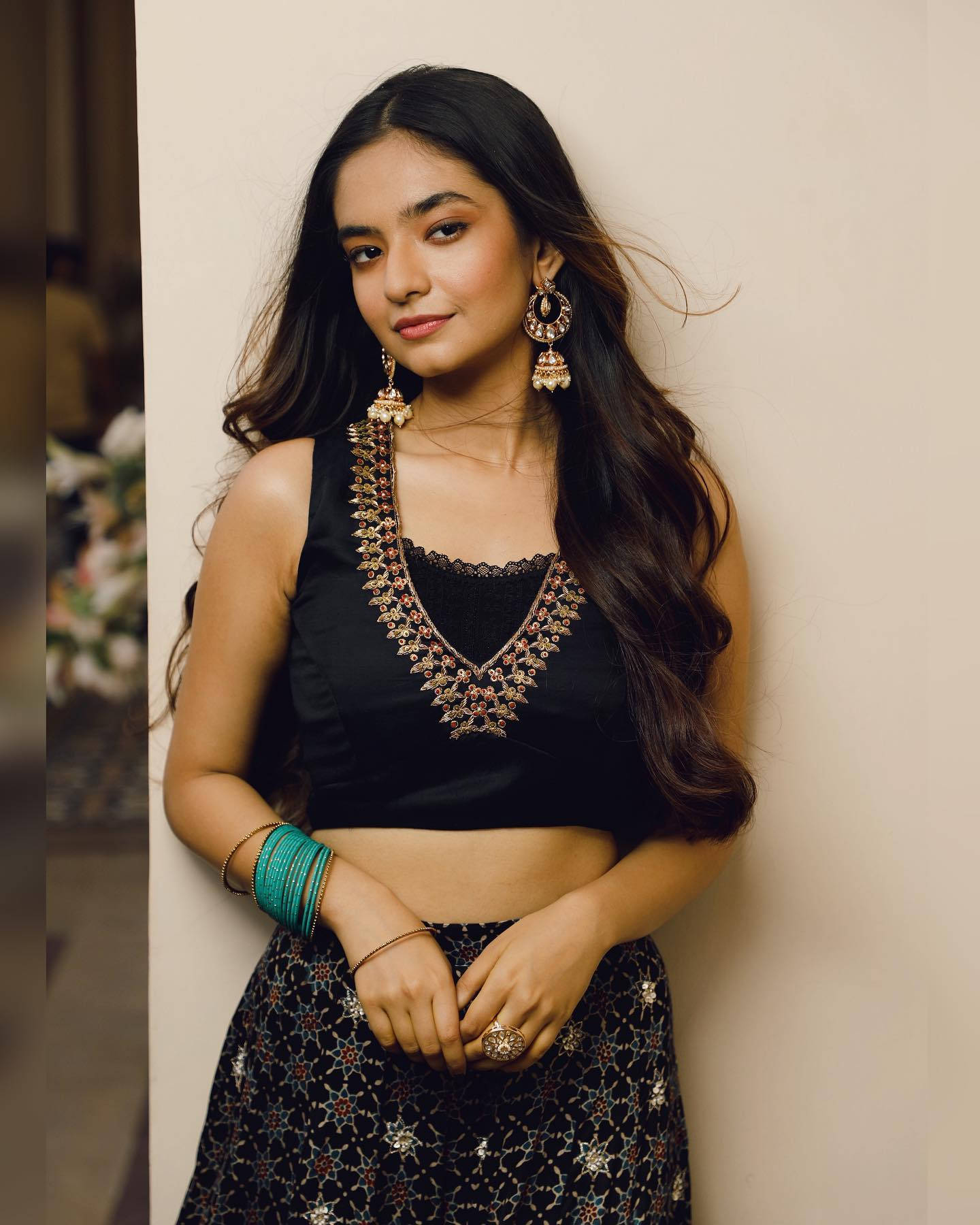 Indian 桌布 壁紙 — 一位長黑髮的女性穿著黑色裝飾短上衣和圖案裙子，靠著牆。