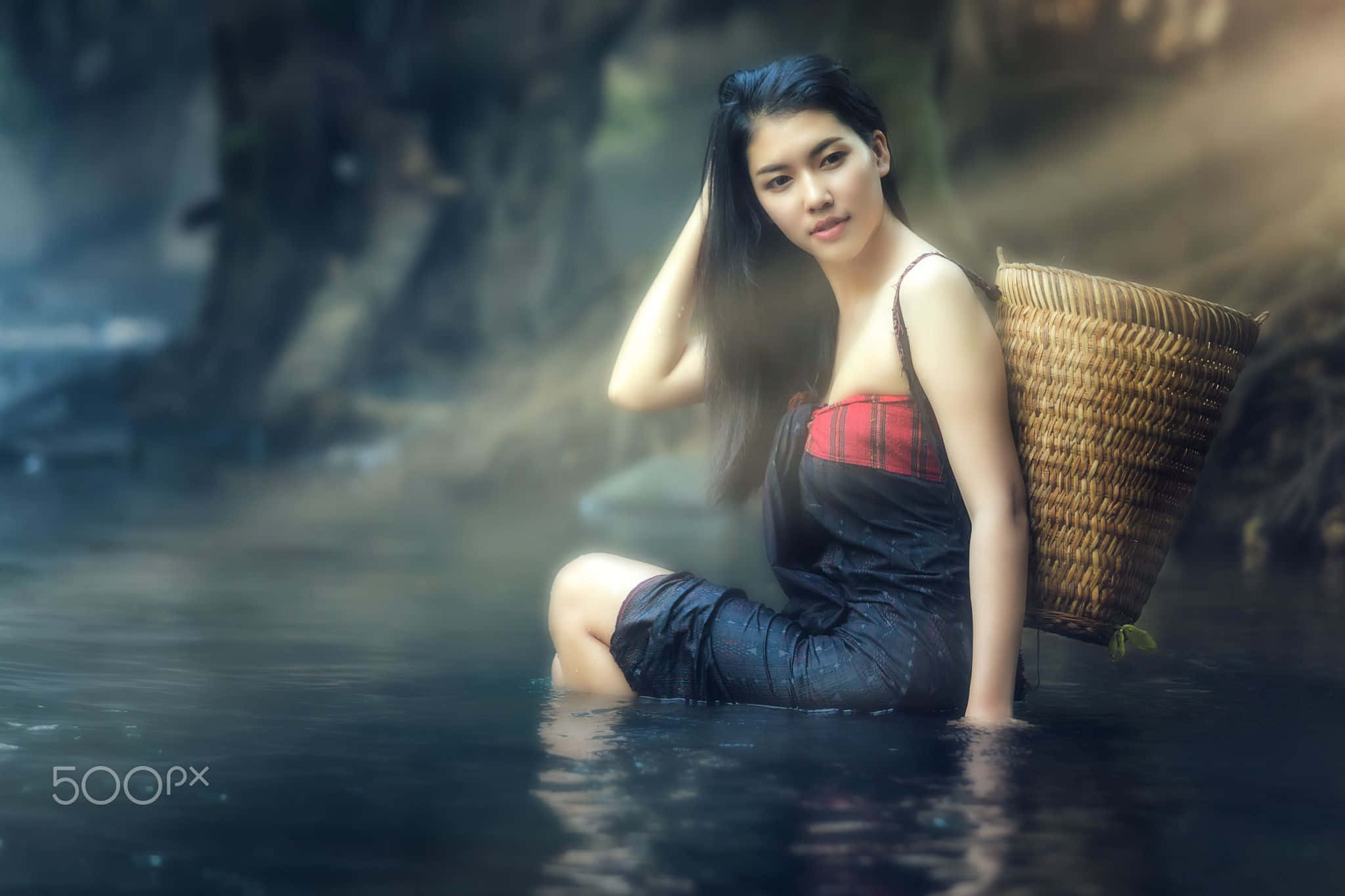 森林 桌布 壁紙 — 一位長黑髮的寧靜女性坐在霧氣瀰漫的水中，手持編織籃，平靜地凝視鏡頭。