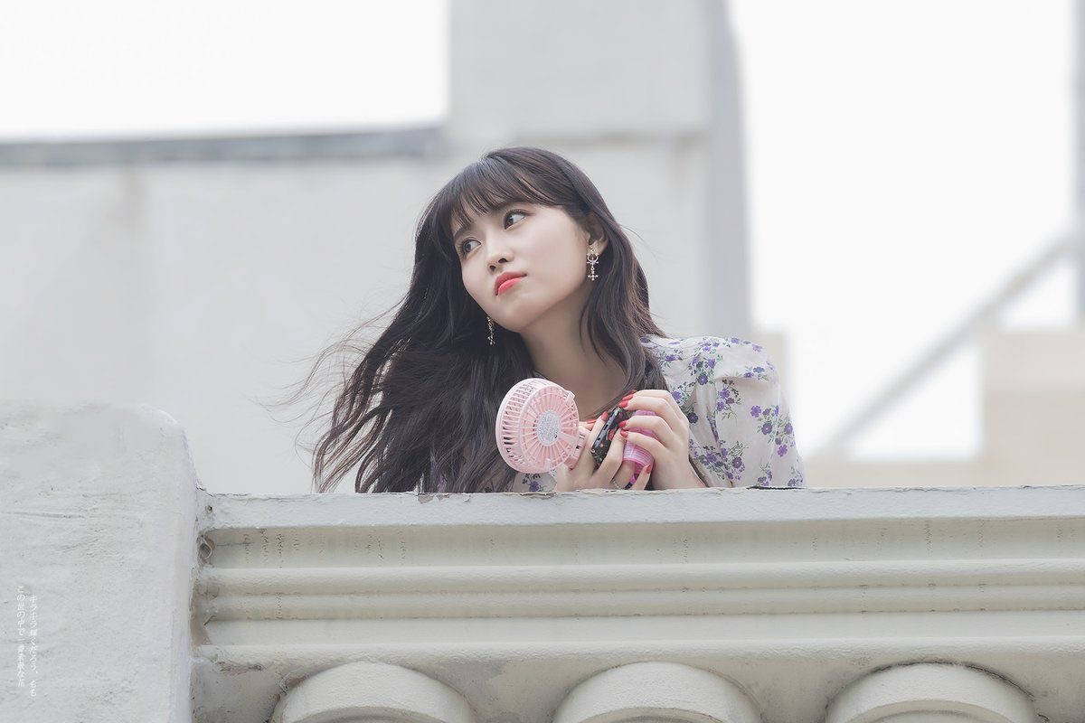 Momo 桌布 壁紙 — 一位長黑髮的年輕女子靠在石陽台上，手持粉紅色手扇，向上凝視。