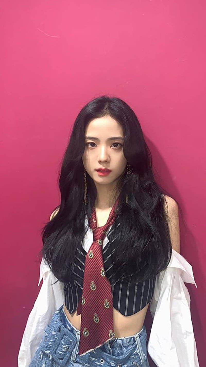 Jisoo Cute 桌布 壁紙 — 一位長黑髮的年輕女性，在鮮豔的粉紅色牆壁前戴著紅色領帶和牛仔褲。