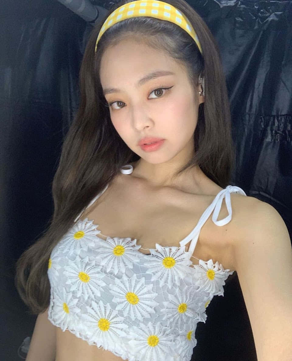 BLACKPINK 桌布 壁紙 — 一位長黑髮的年輕女性，在黑色背景下穿著白色雛菊圖案短版上衣和黃色格紋頭帶。