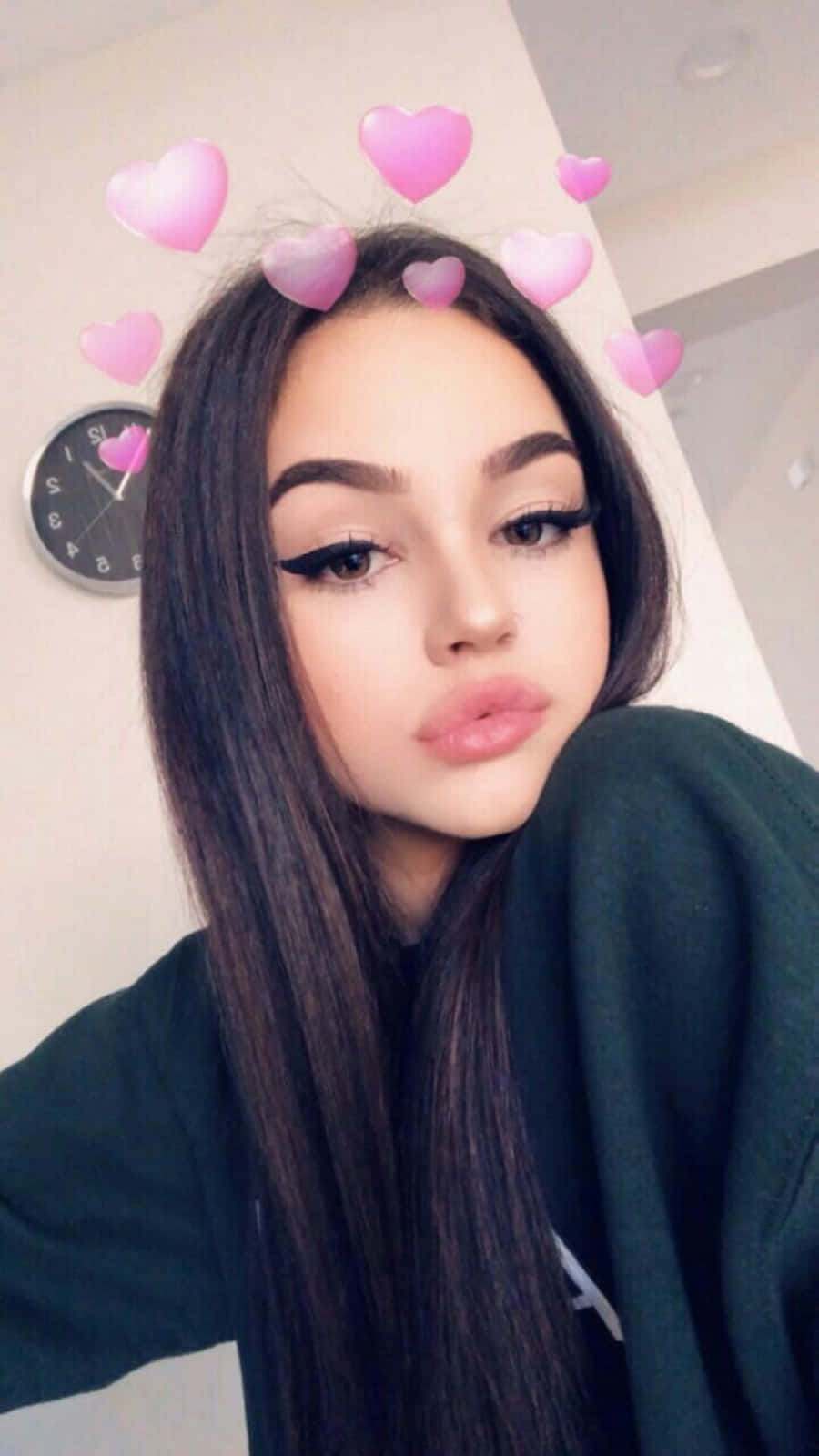 Snapchat 桌布 壁紙 — 一位長黑髮的年輕女性使用心形濾鏡在室內自拍，背景有時鐘。