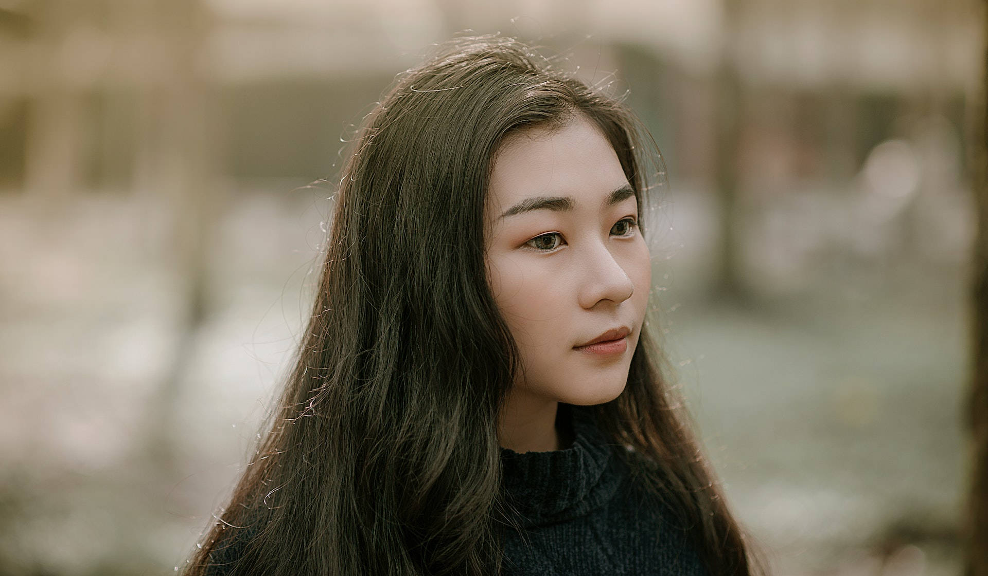lovely girl 桌布 壁紙 — 一位長黑髮的年輕女性在柔和的自然光下於戶外若有所思地凝視。