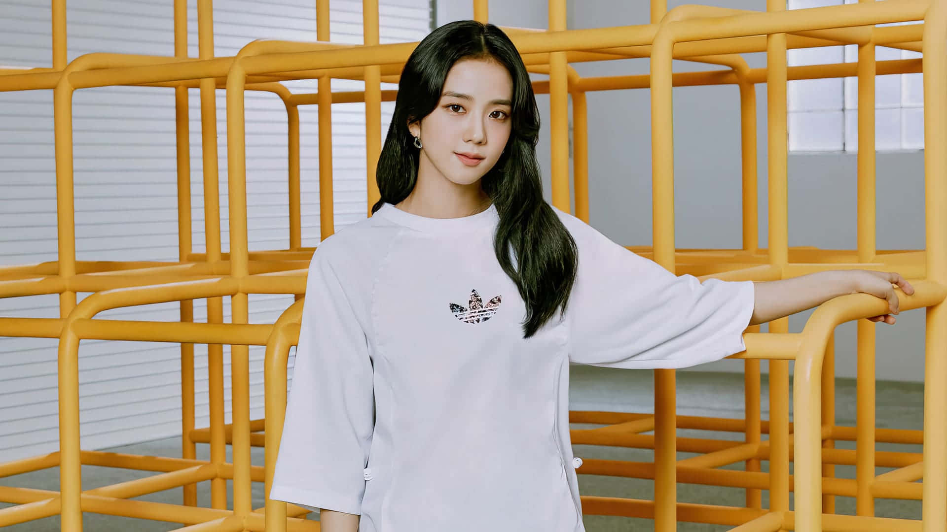 穿白色T恤的年輕女性在室內倚靠在黃色金屬結構上。 — 智秀 GIF 壁紙