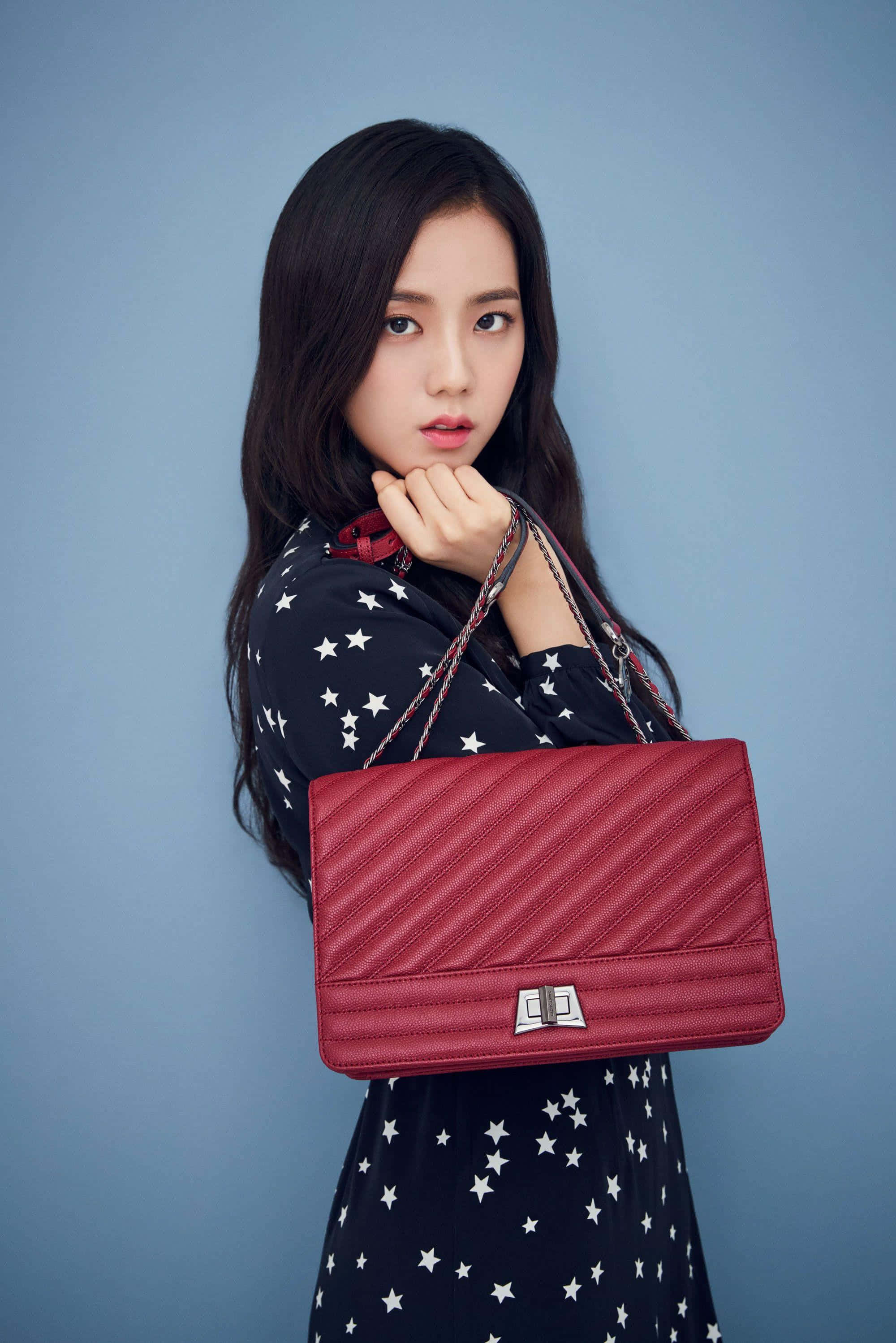 BLACKPINK 桌布 壁紙 — 一位長黑髮的年輕女性在純藍色攝影棚背景前，手持紅色絎縫手提包擺姿勢。