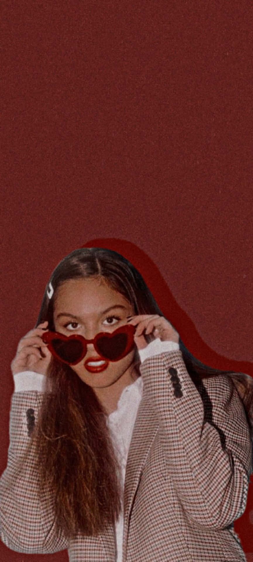 Olivia Rodrigo Aesthetic 桌布 壁紙 — 一位長黑髮的年輕女性戴著心形紅色太陽眼鏡，背景為純深紅色。
